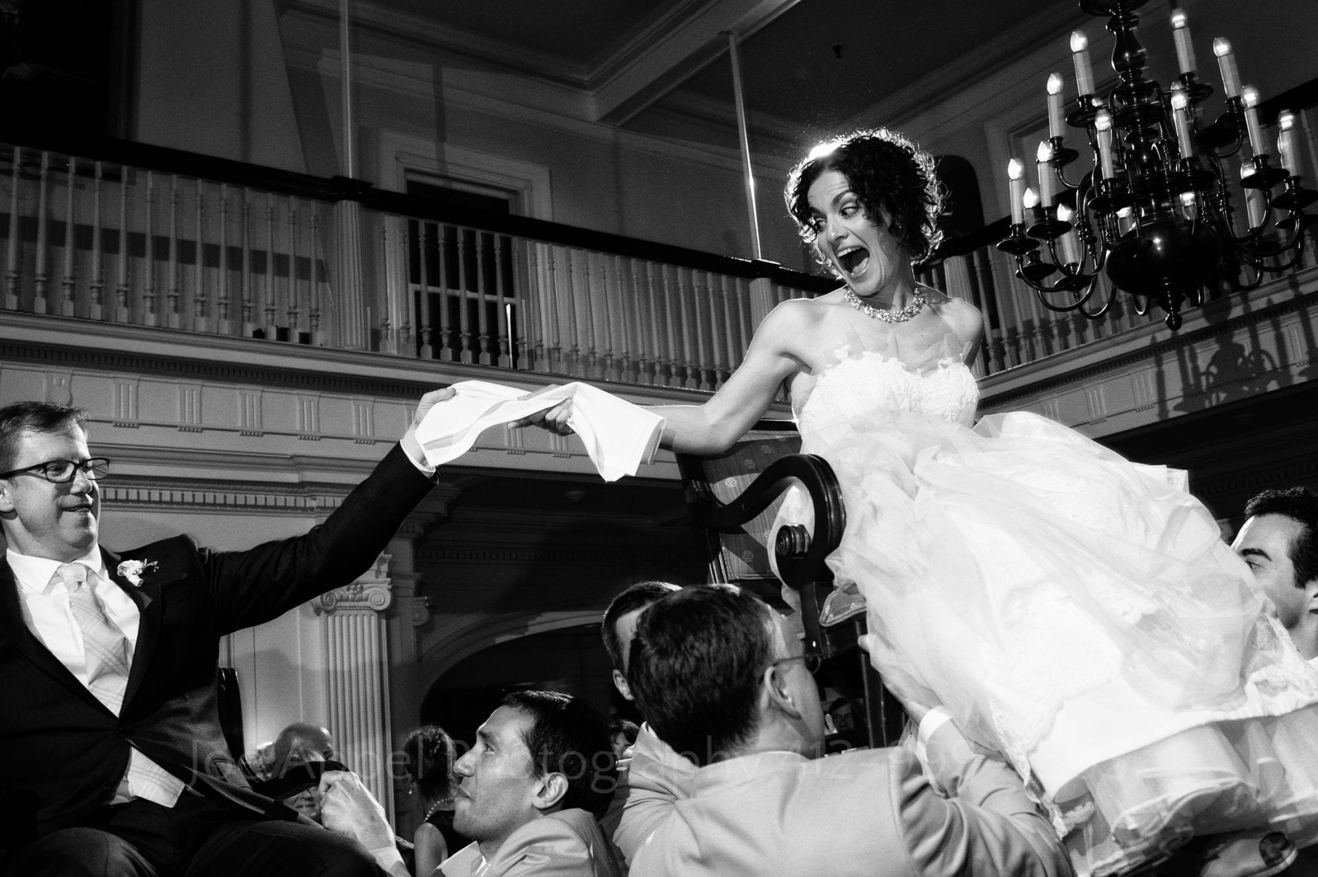 a bride and groom hold hands and laugh as they are lifted on chairs during their Pittsburgh Golf Club Weddings