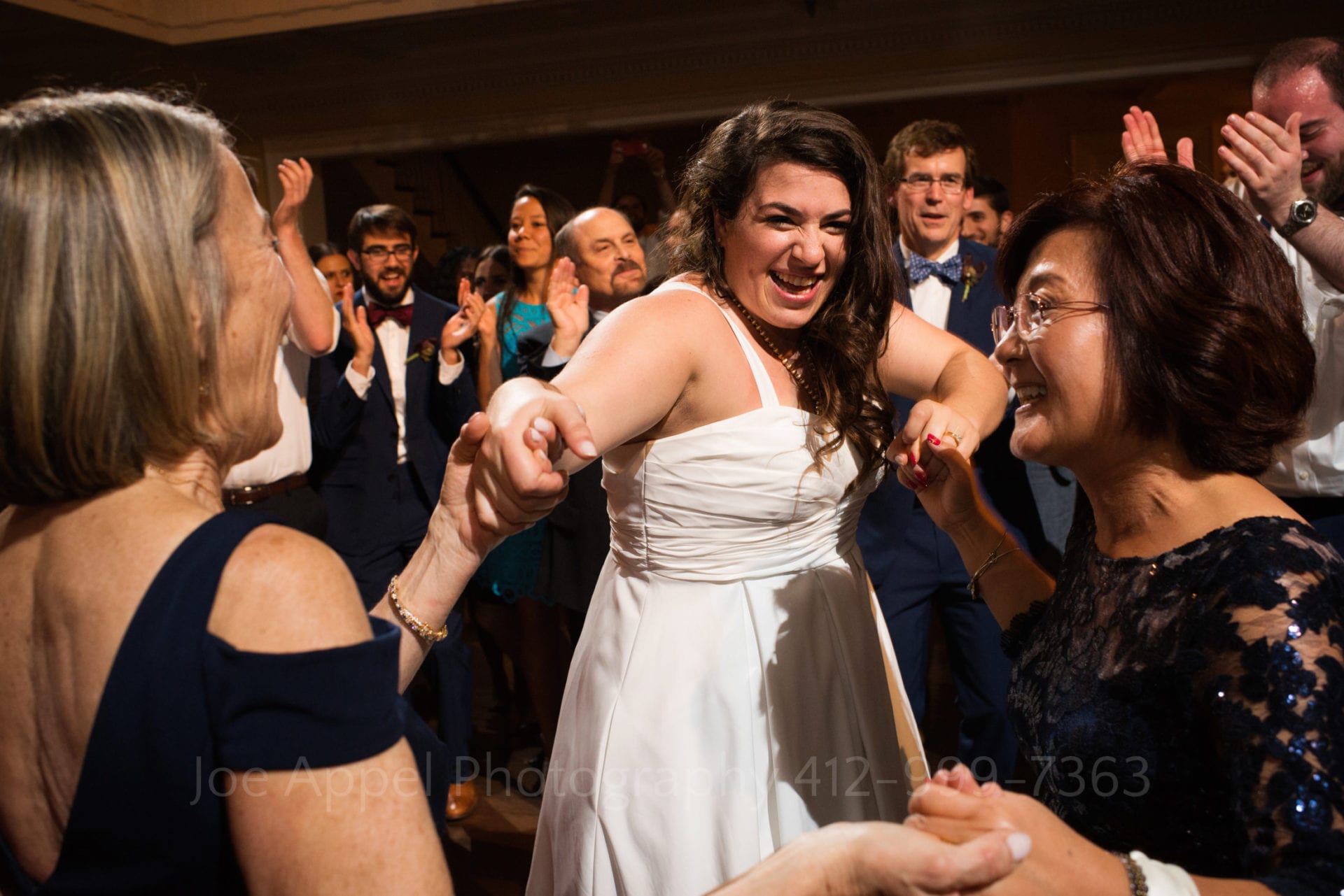 a bride and two women laugh and dance