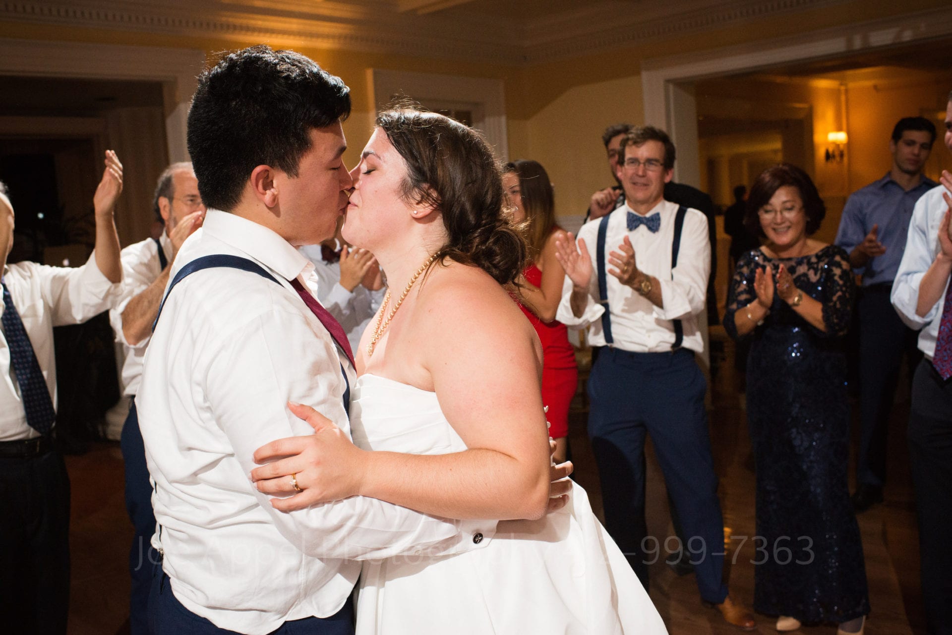 guests applaud a bride and groom as they kiss and dance