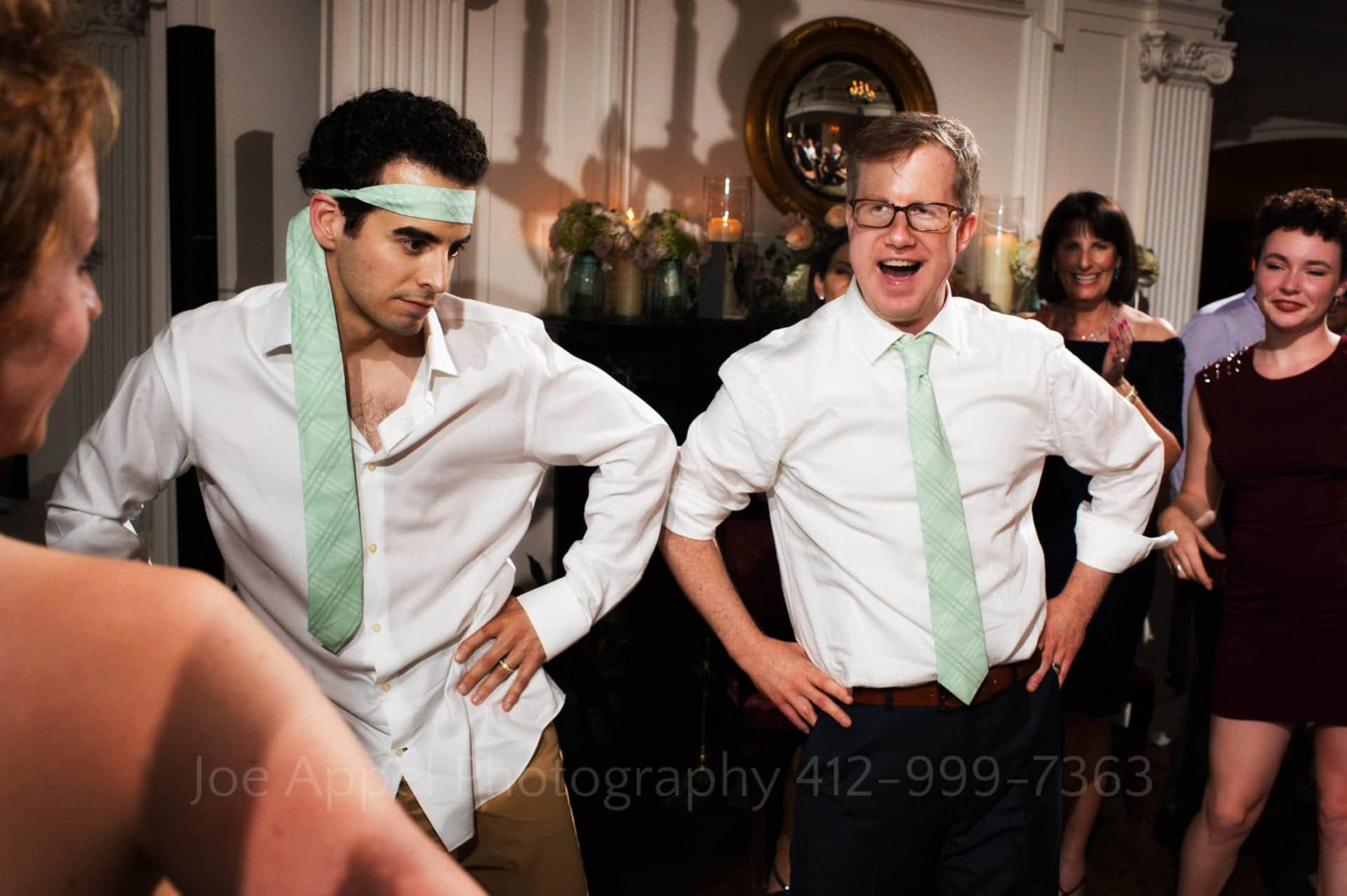 a man with a green tie wrapped around his head dances with the groom
