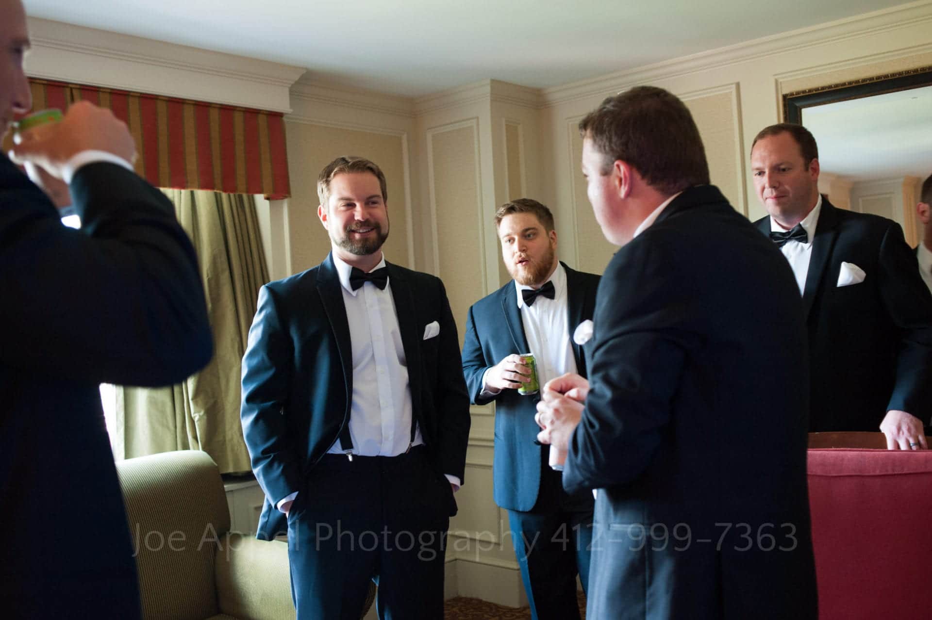 a groom and his groomsmen stand together in their tuxedos