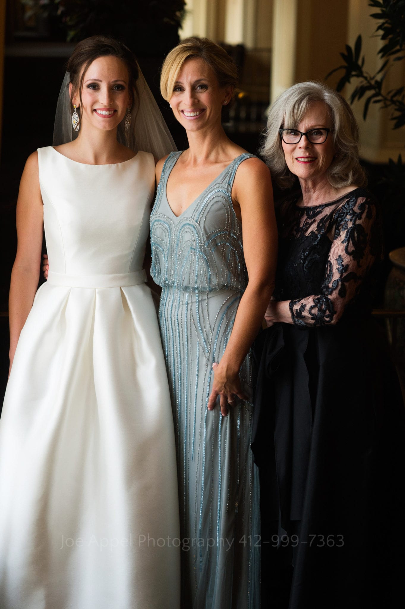 a bride poses and smiles with her mother and sister
