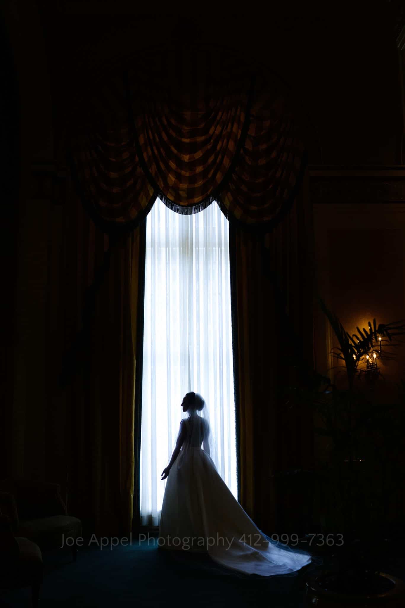 a bride stands in front of an illuminated window