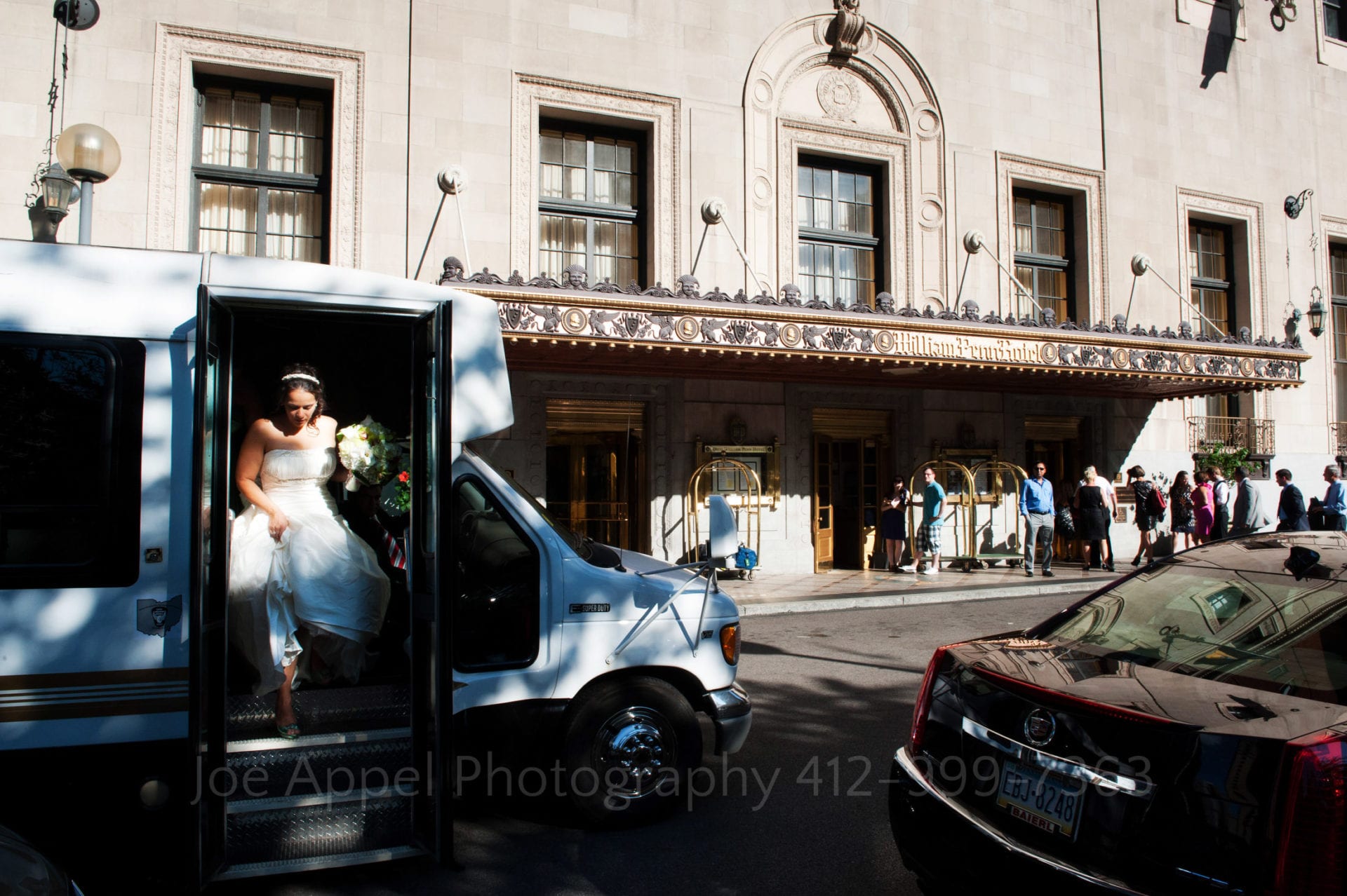 a bride gets out of the van in front of the william penn hotel