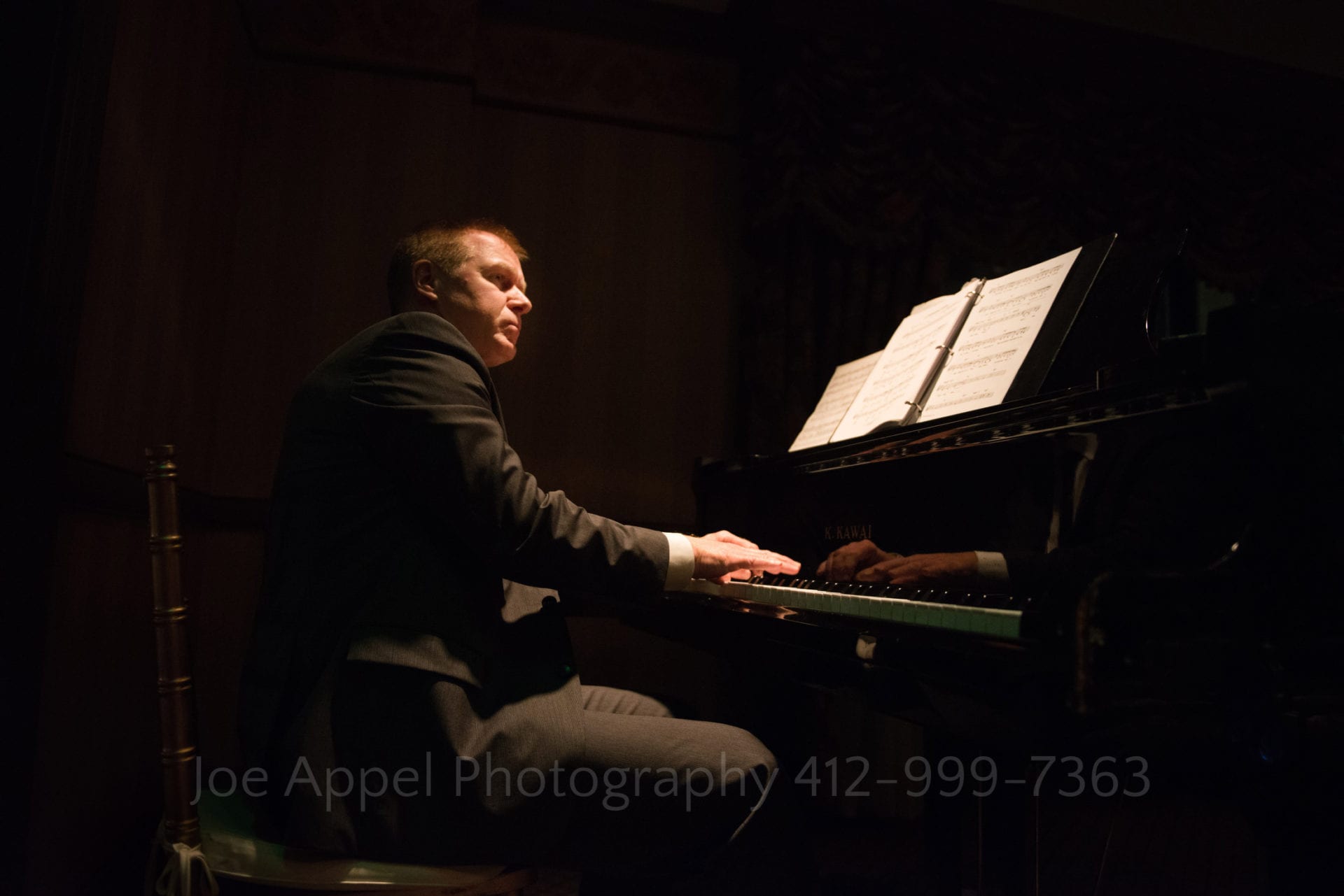 a man plays the piano in a dark room