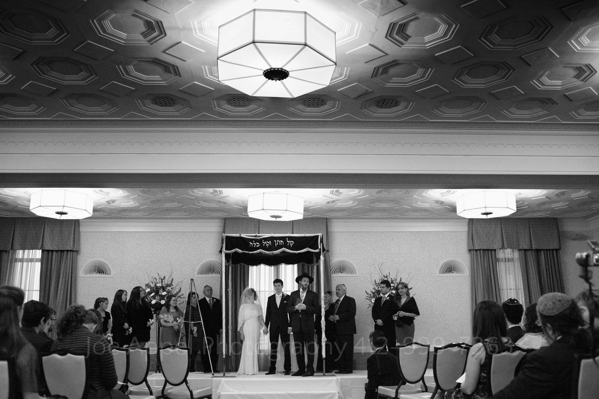 a bride and groom stand under their chuppah with guests