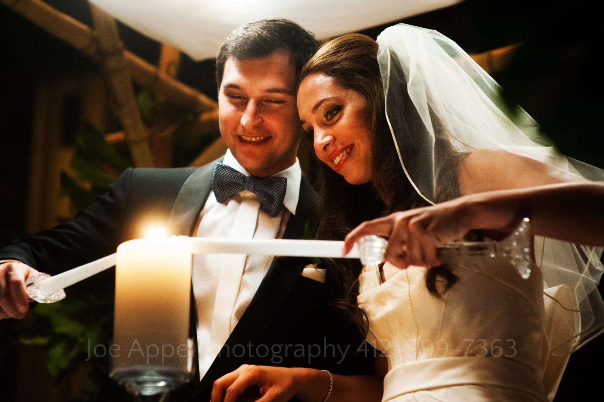 a bride and groom smile and light candles together