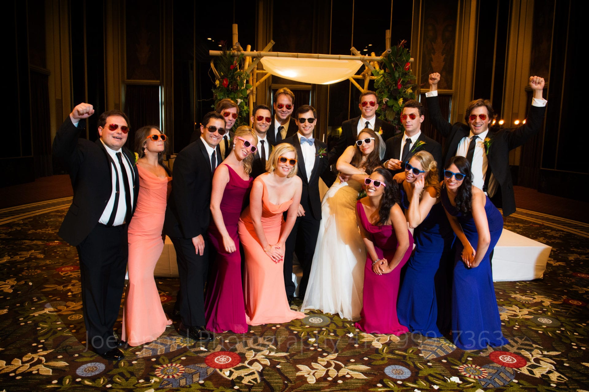 a wedding party wearing colorful sunglasses stands together