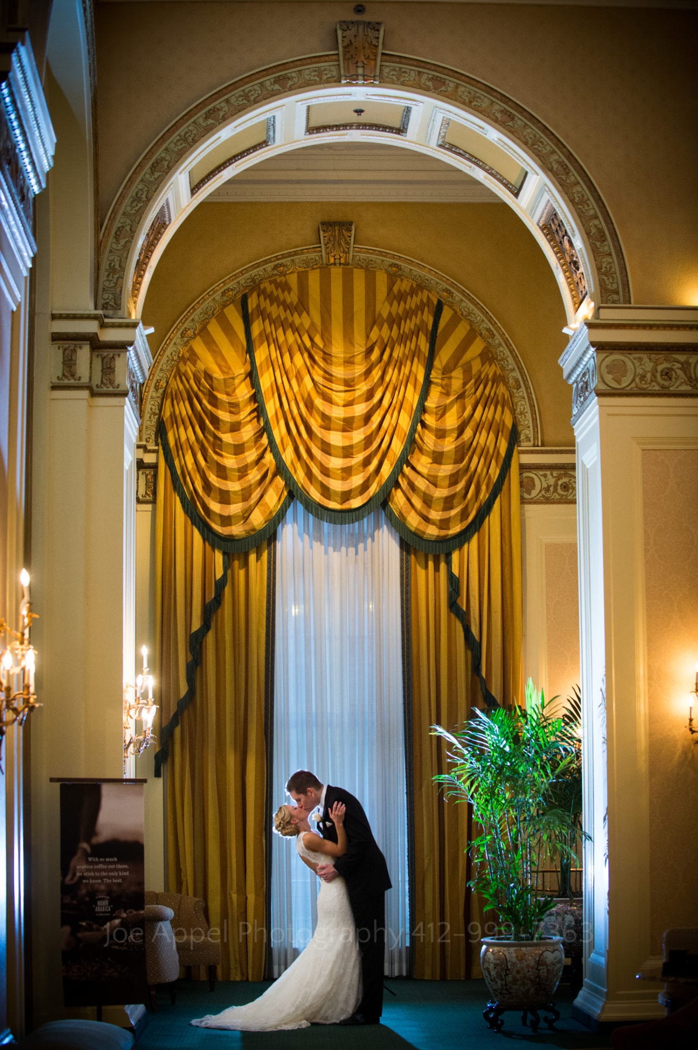 a bride and groom kiss in front of a yellow curtain