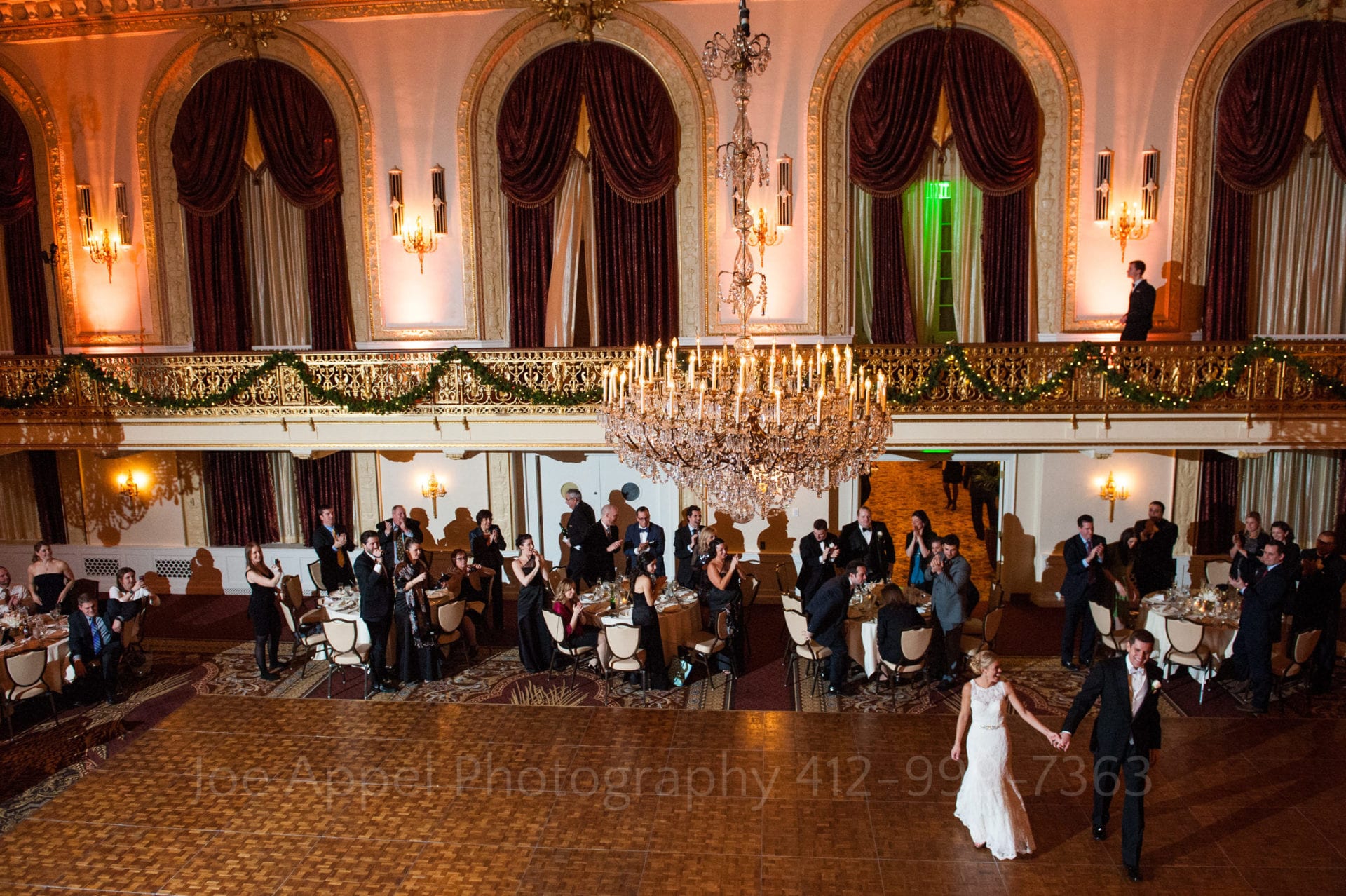 a bride and groom enter the dance floor in their red white and gold ballroom