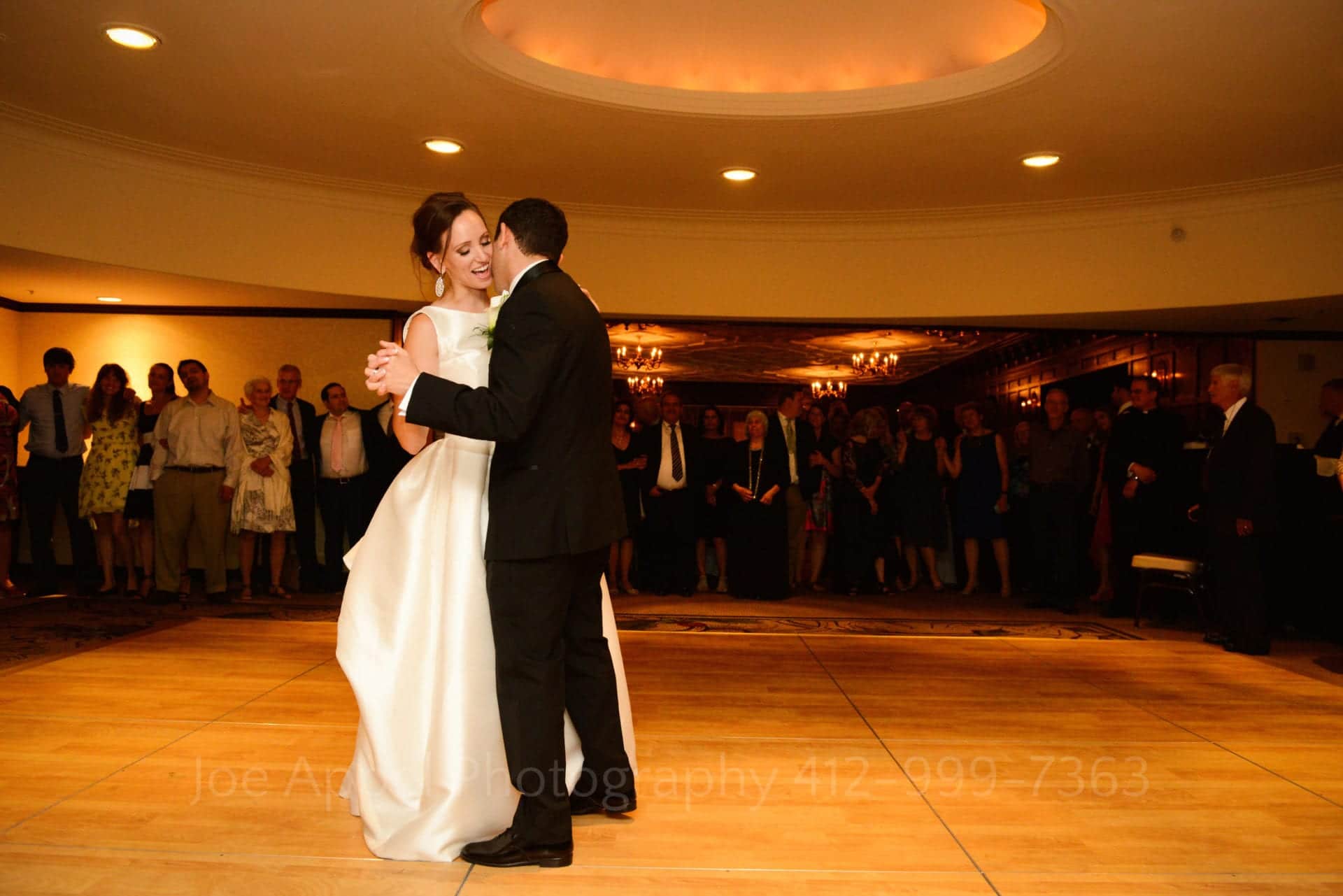 a groom kisses his brides cheek as they slow dance