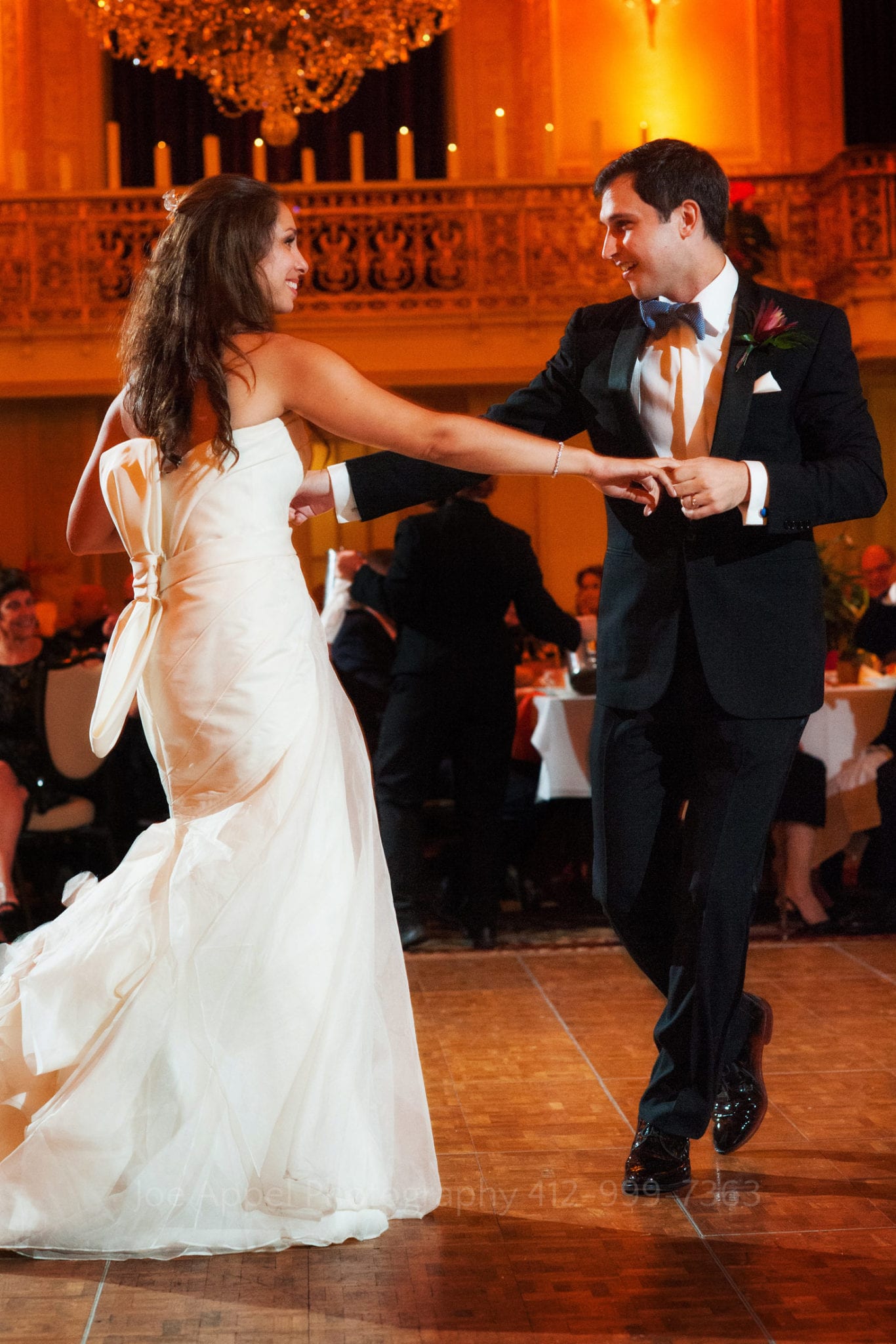 a bride and groom hold hands and dance