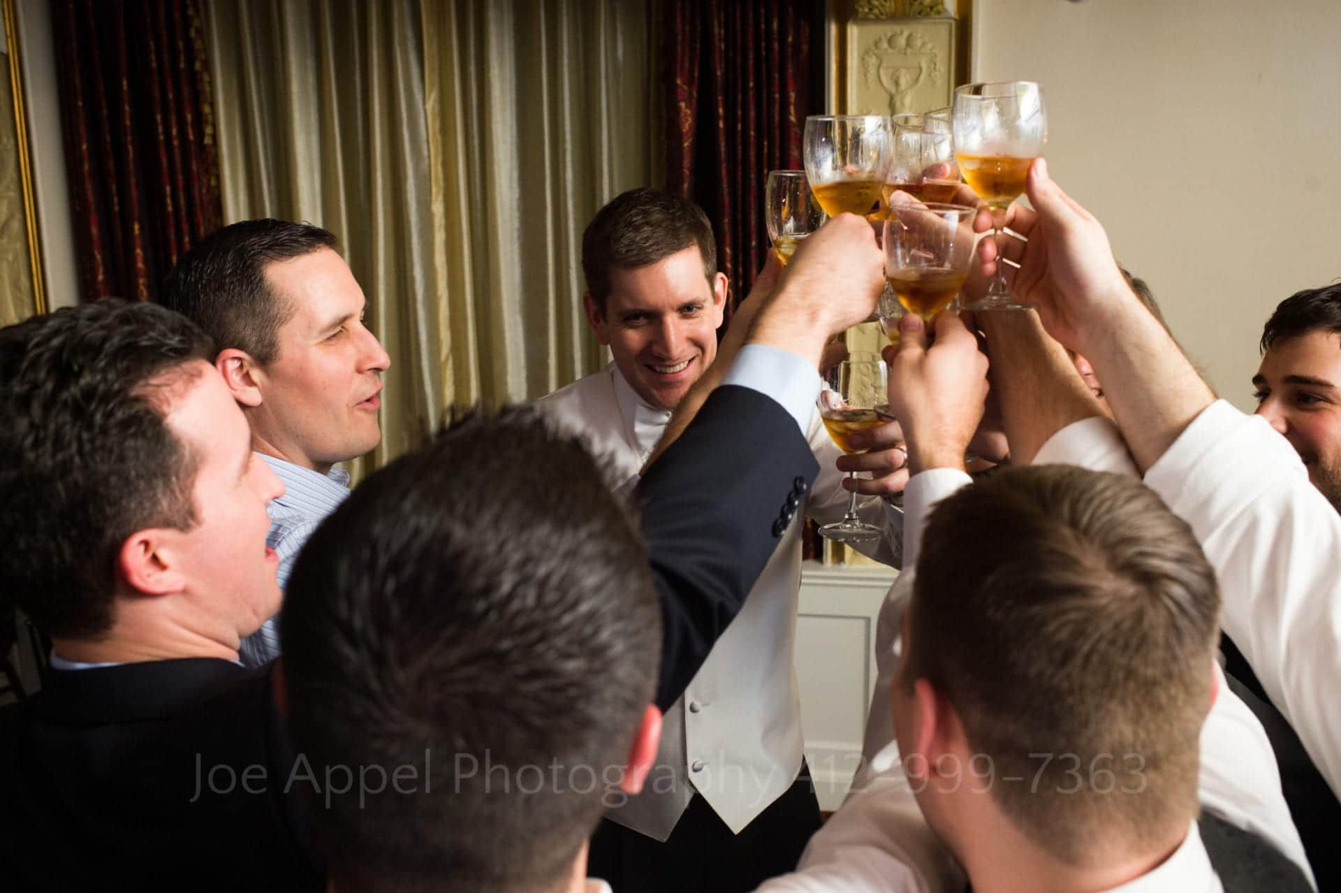 a groom smiles and makes a toast with his groomsmen