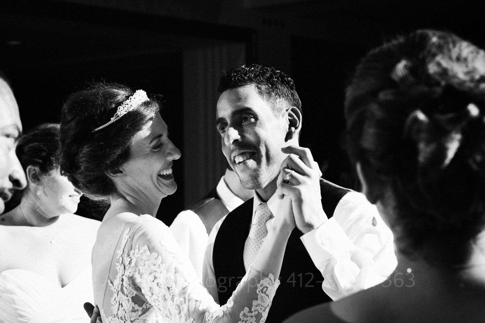 a bride with a tiara smiles and dances with her groom