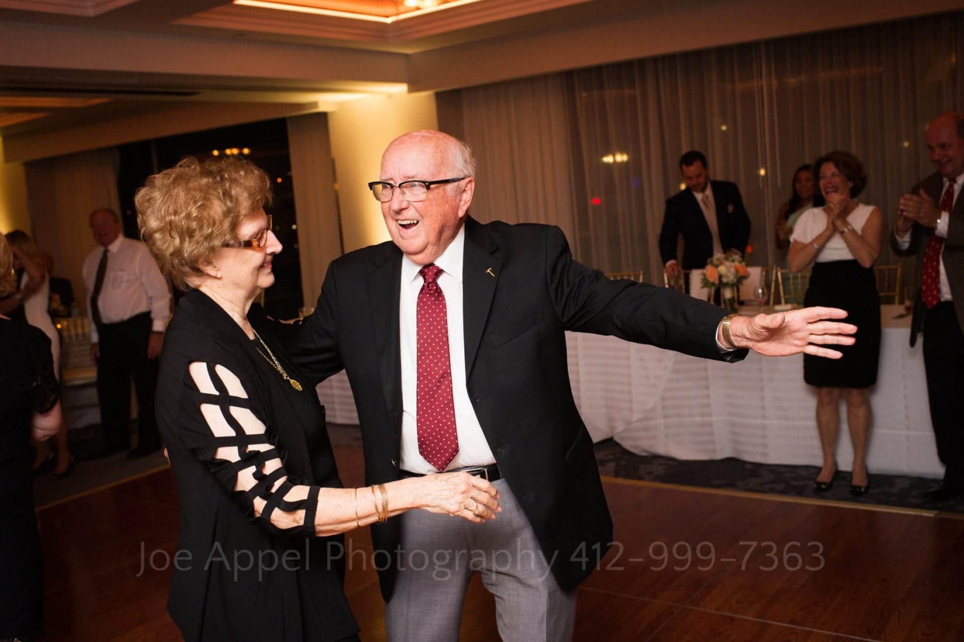 an elderly couple smiles and dances