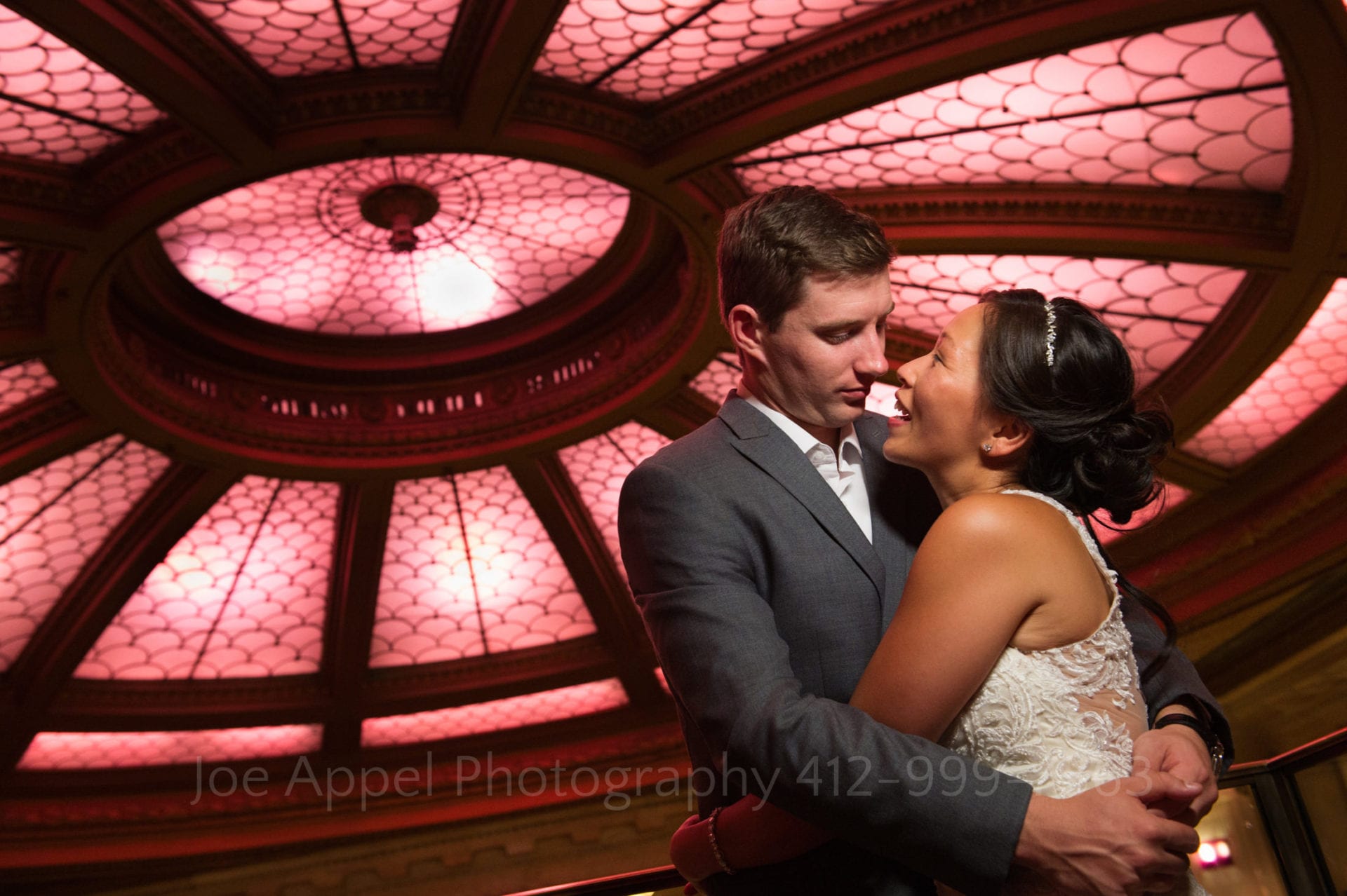 a bride and groom embrace under the skylight at their Renaissance Pittsburgh wedding.