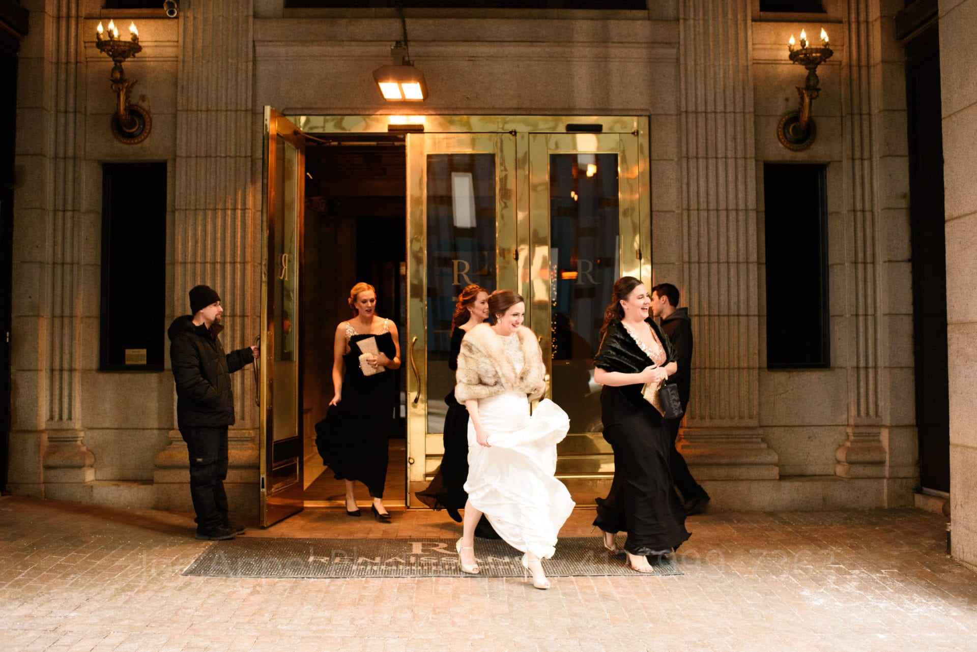 bridesmaids in pink sequin dresses and black shawls leave the hotel with a bride wearing a fur shawl