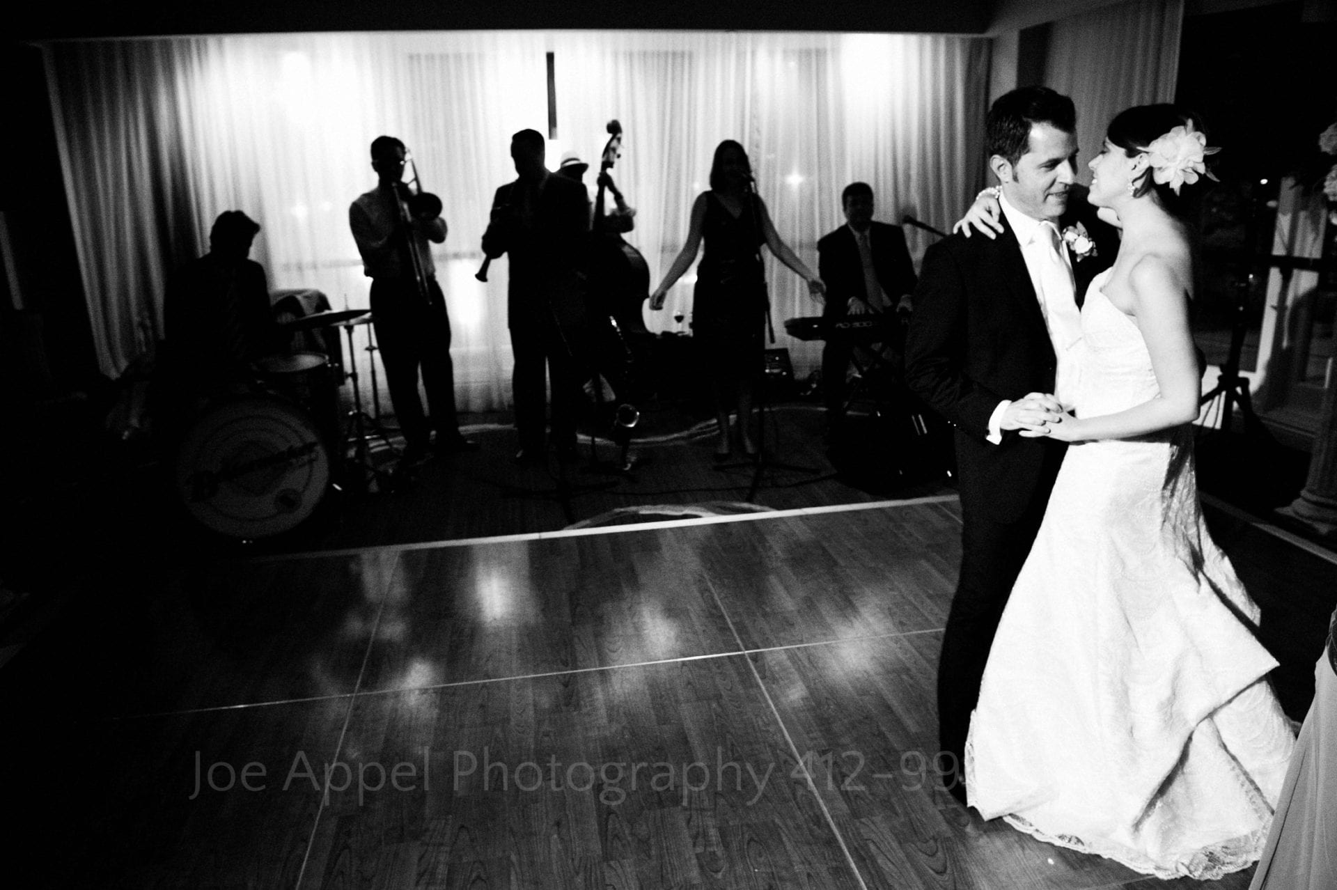 a bride and her father dance while the wedding band plays