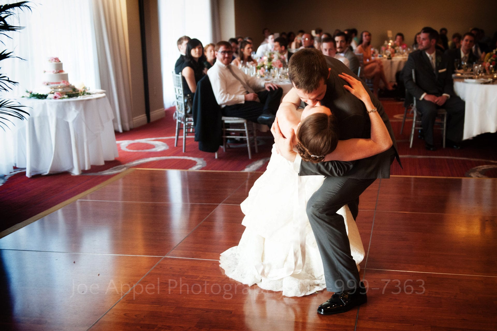 guests watch a groom dip his bride and kiss her