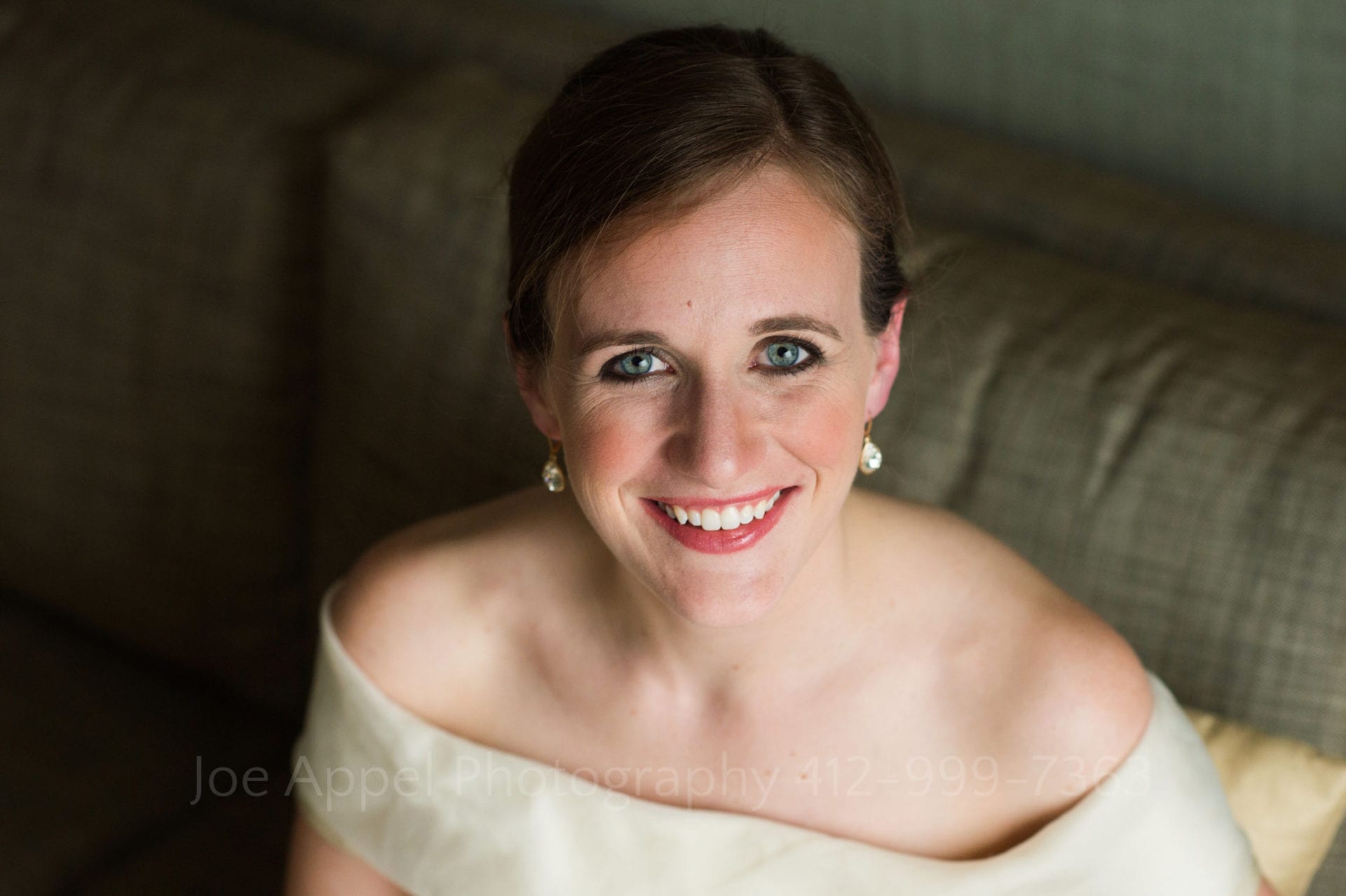 A smiling bride with striking blue eyes looks at the camera before heading to her Heinz History Center wedding.