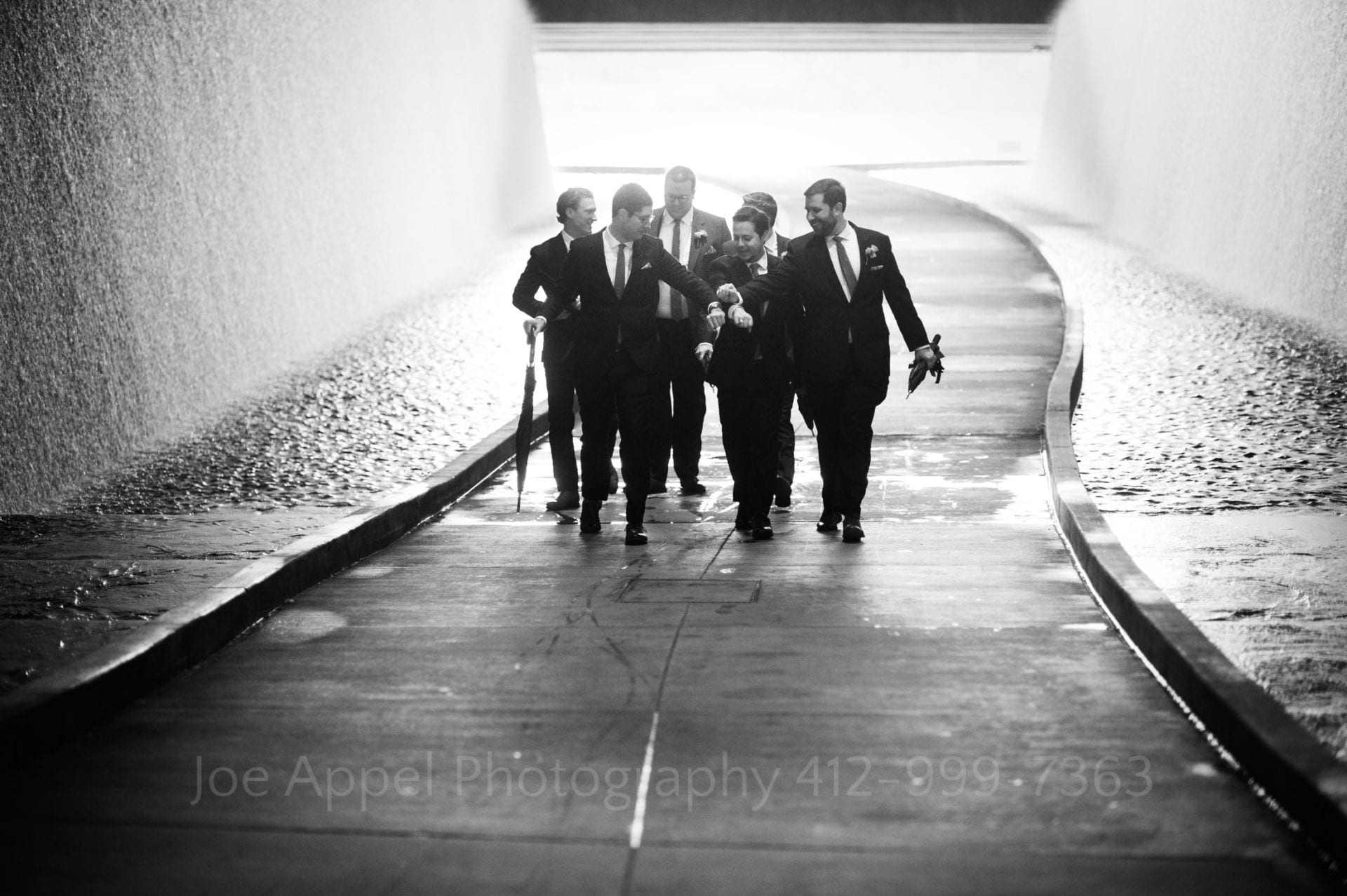 A group of men in suits walk up the path beneath the D.L. Lawrence Convention Center.