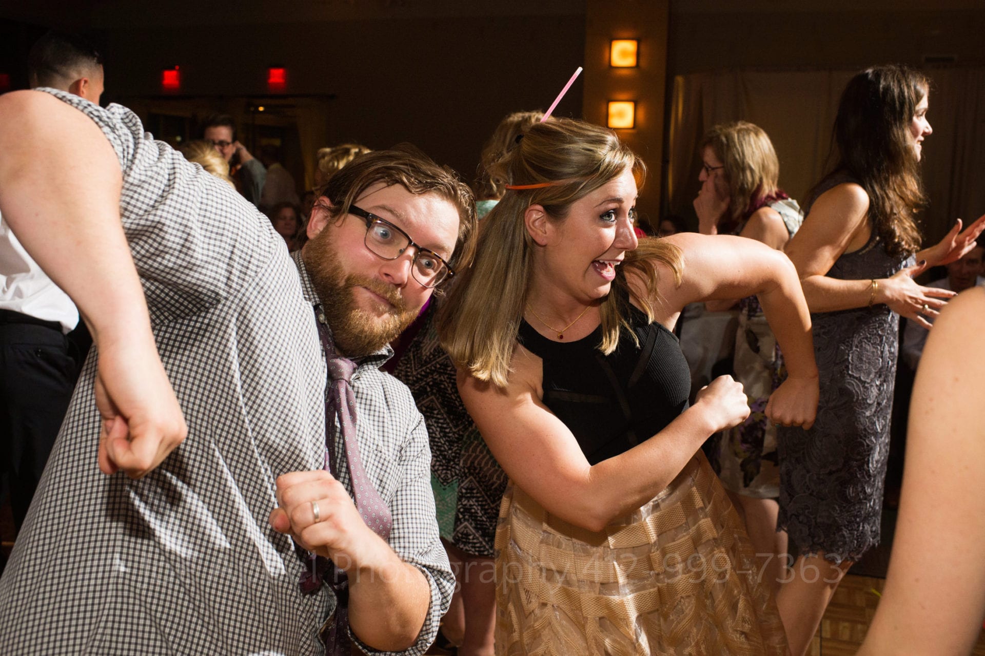 A couple dances together with amused faces as they throw their elbows into the air during a Heinz History Center wedding.