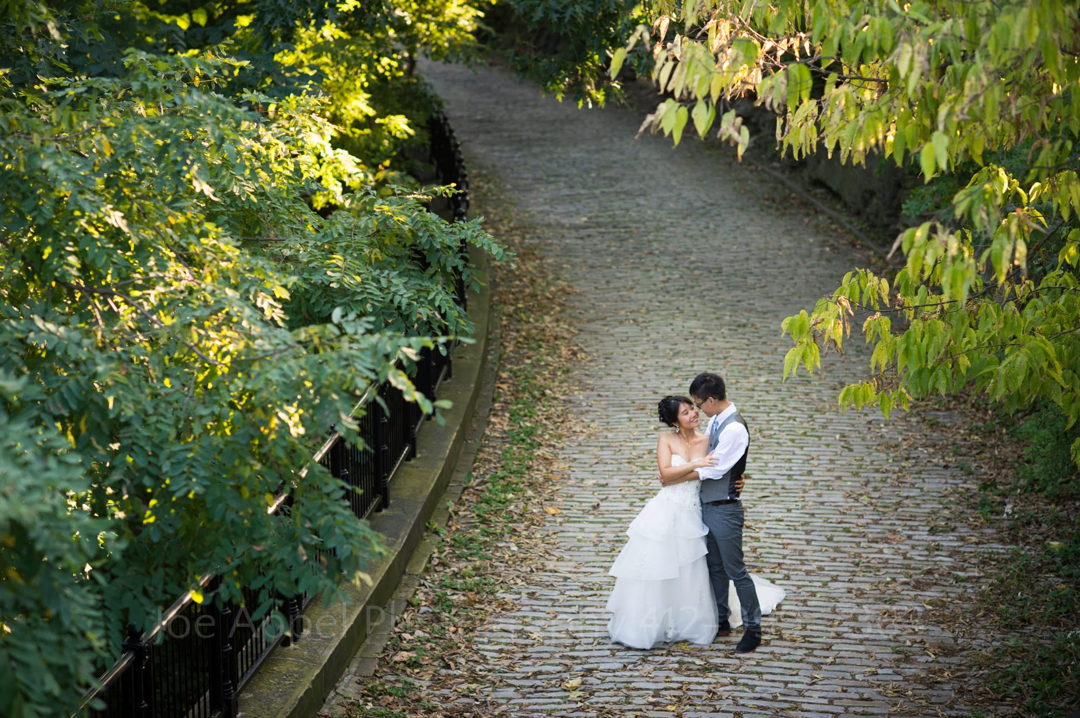 a bride and groom stand on a cobblestone street near Schenley Park Cafe and Visitors Center