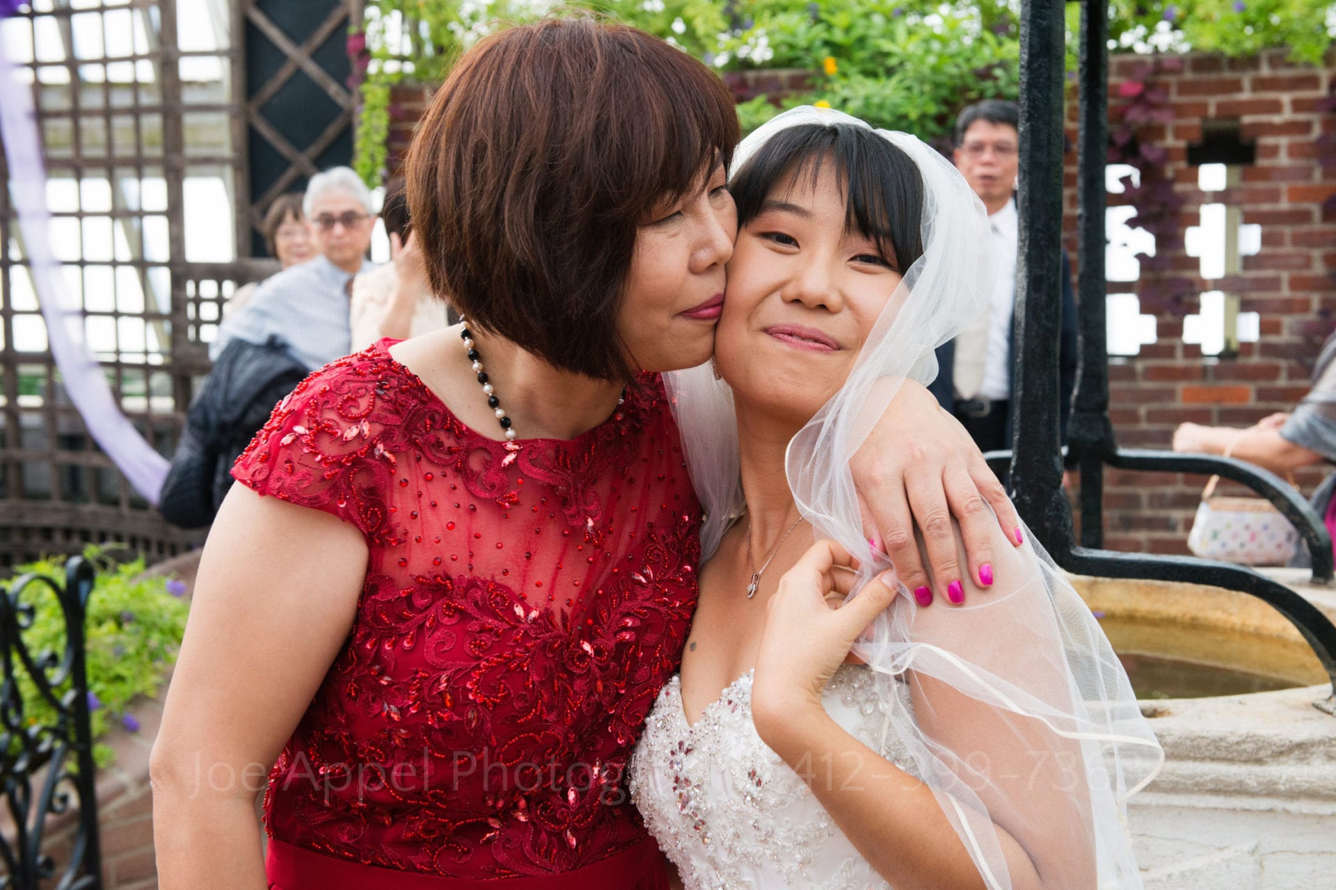 the brides mother wears a red dress and hugs her daughter after her Phipps conservatory wedding.