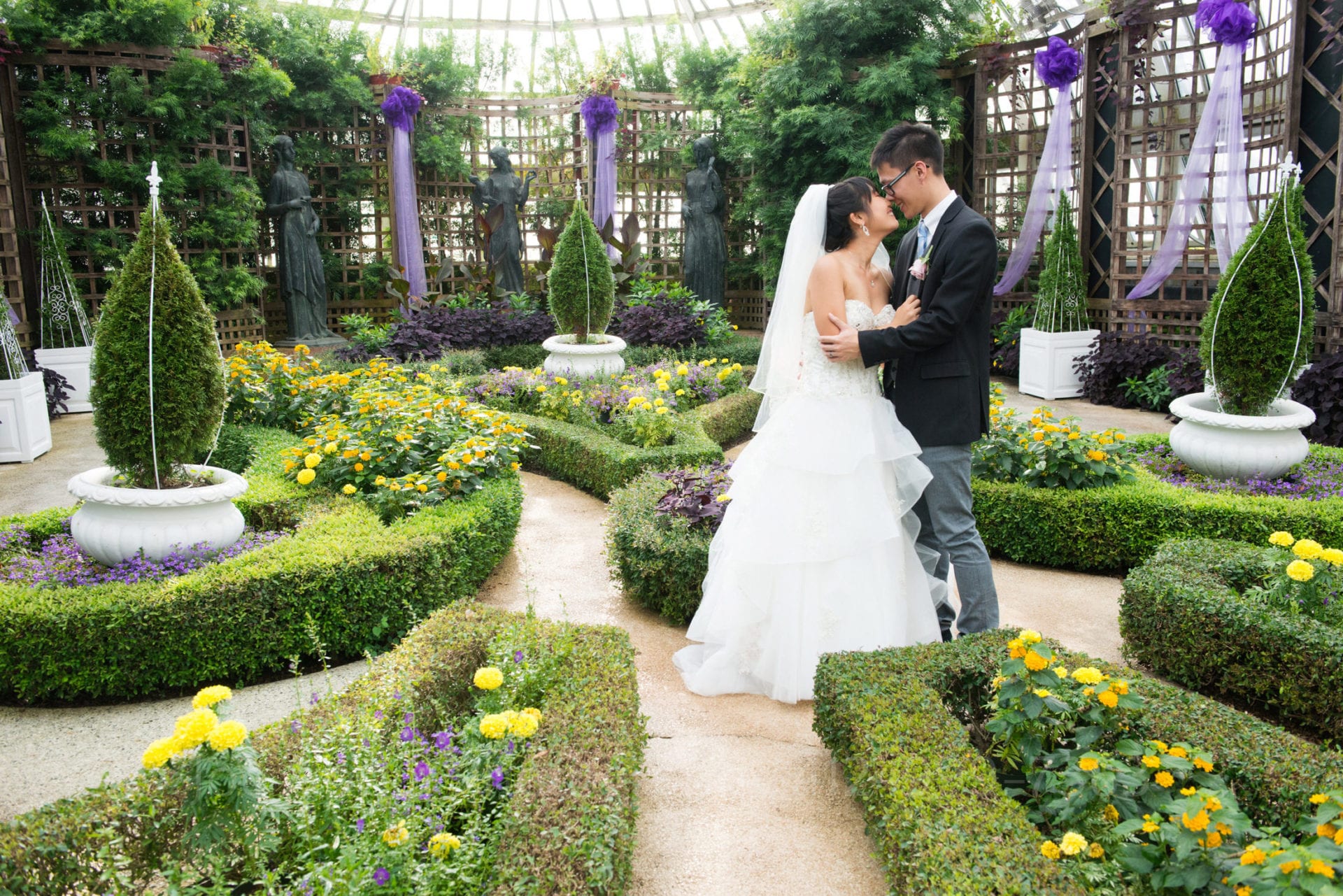 a bride and groom embrace in a garden with purple accents after their phipps conservatory wedding in the broderie room.