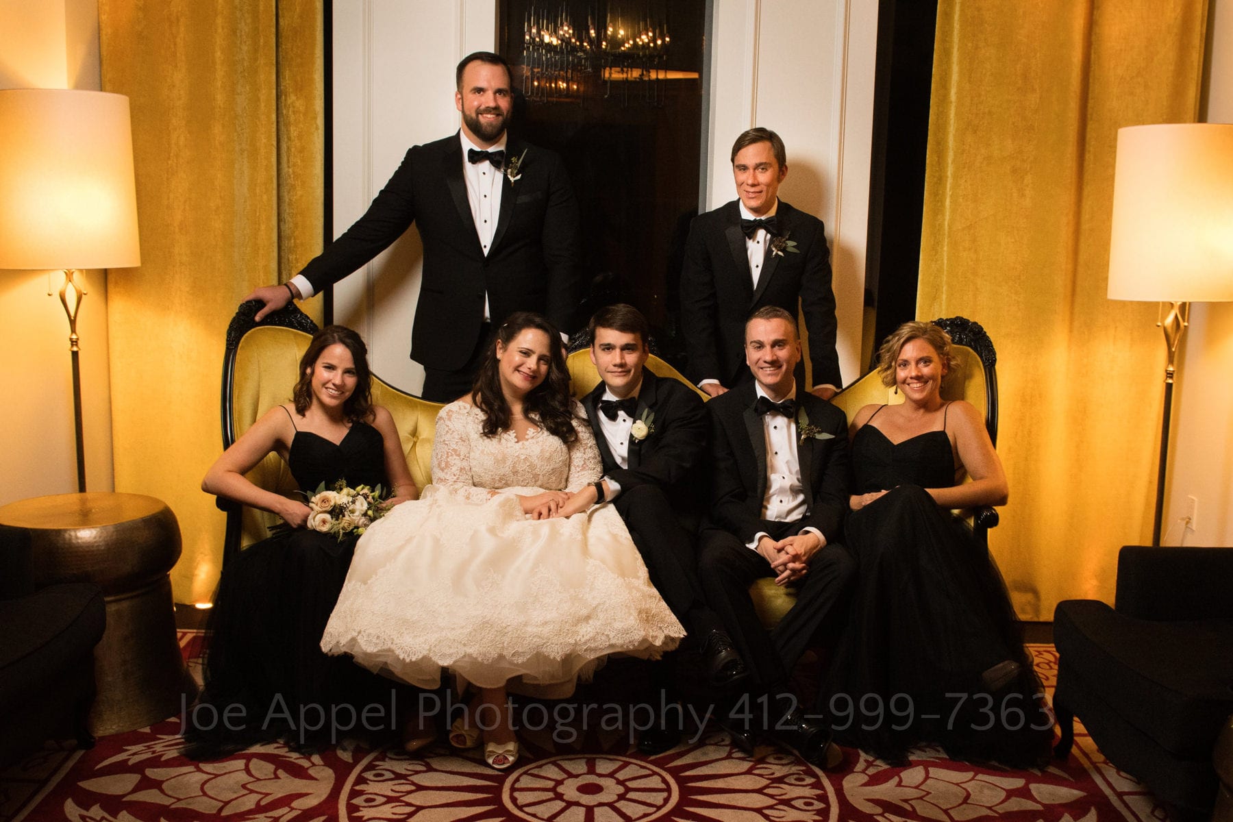 a bride and groom sit on a yellow couch with their wedding party at the hotel monaco pittsburgh wedding