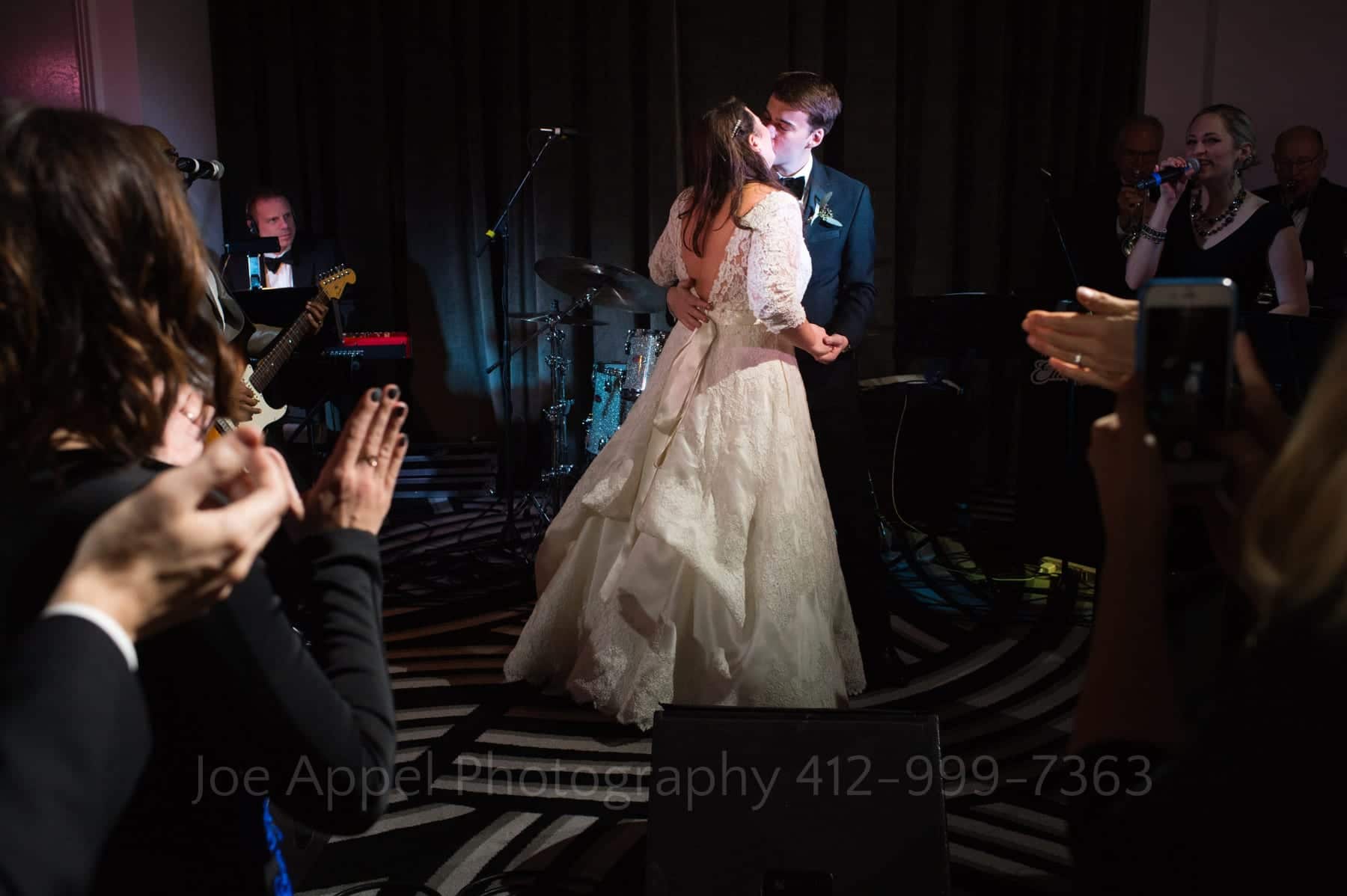 guests clap as the bride and groom dance and kiss under a spotlight at the end of the evening at the hotel monaco pittsburgh wedding
