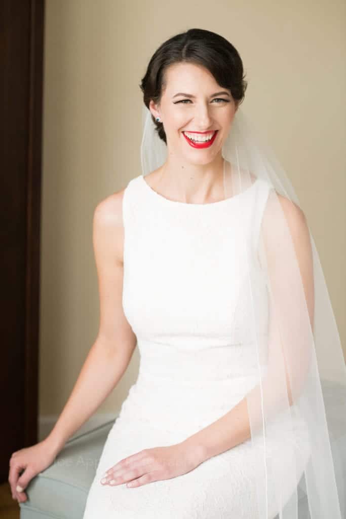 A bride smiles as she sits in her strapped wedding gown and veil before her St Francis Hall Washington DC wedding.
