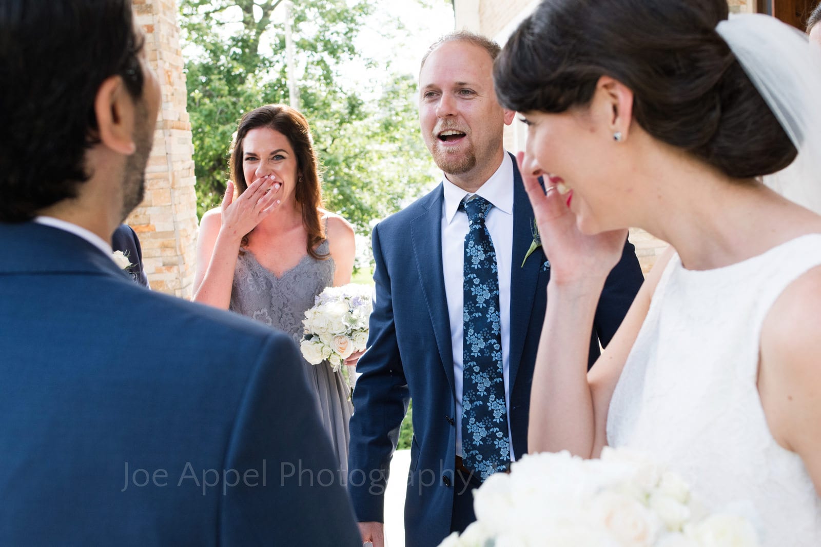 A bride wipes a tear as she and her groom are congratulated by a groomsman and a bridesmaid, who is also crying outside of St. Mary's Armenian Apostolic Church in Washington DC.