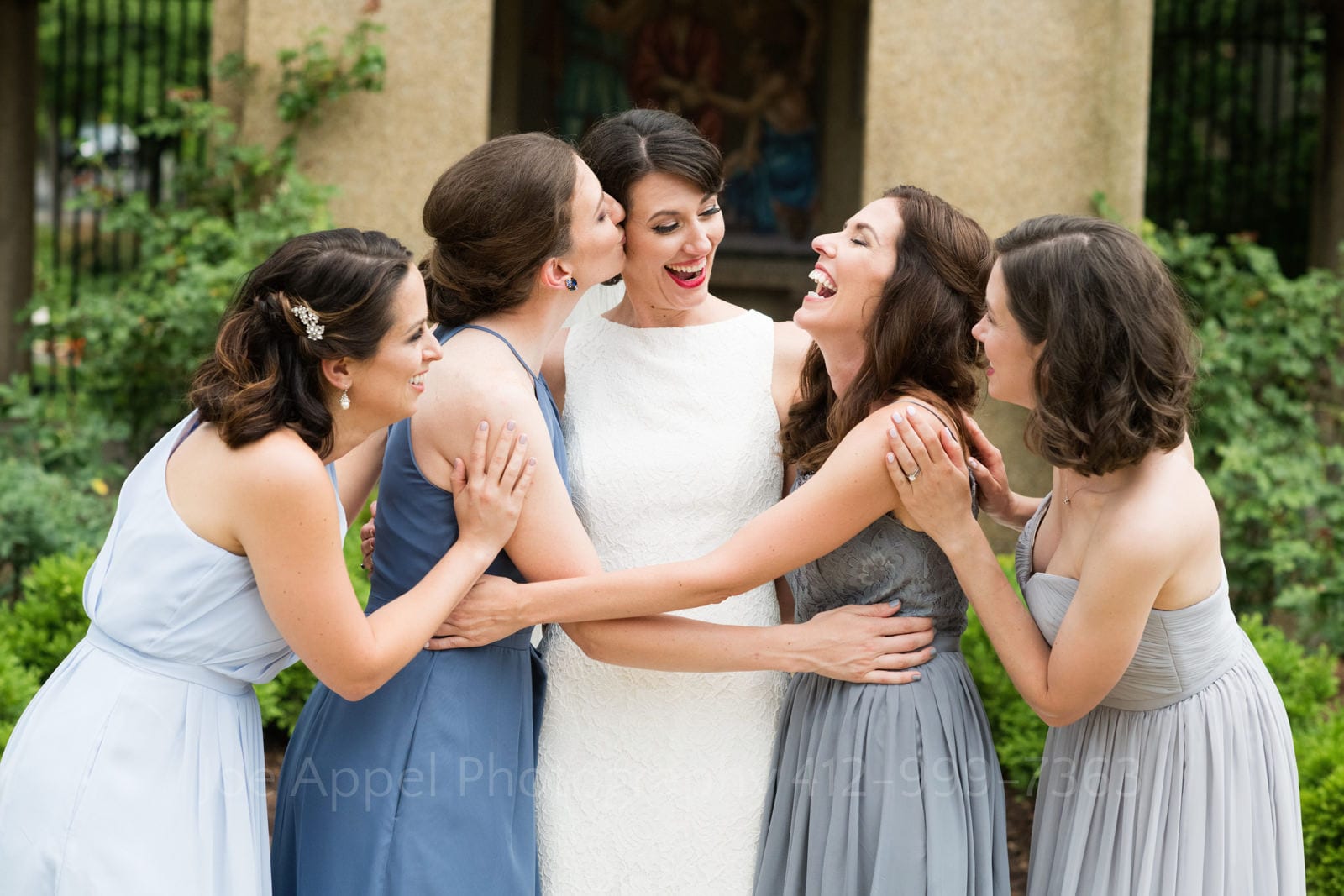A bride laughs as she embraces her bridesmaids outside of her St Francis Hall Washington DC wedding.