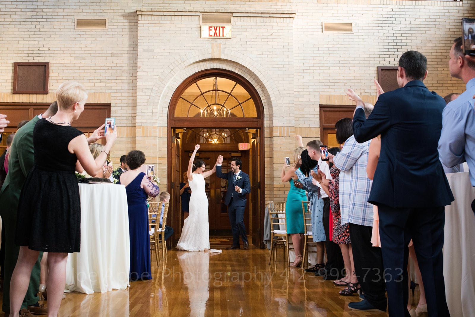 A bride raises her arms in triumph as she and her groom enter their St Francis Hall Washington DC wedding.