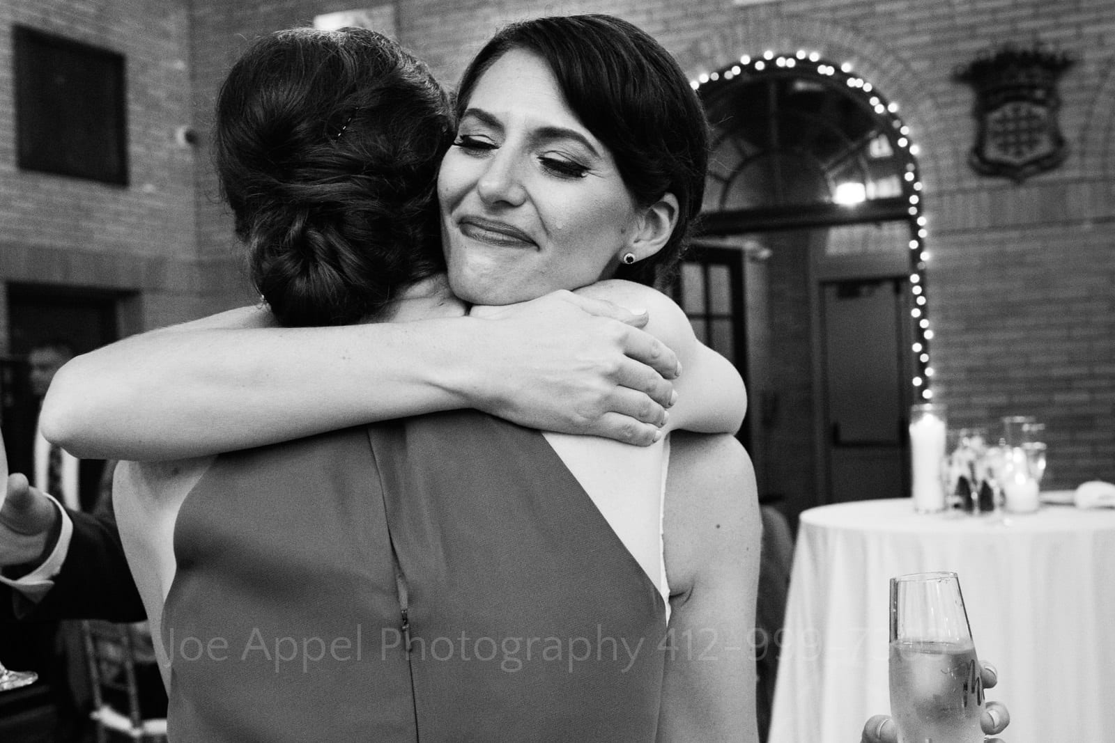 A tear falls down the cheek of a bride as she embraces her matron of honor after a toast at her St Francis Hall Washington DC wedding.