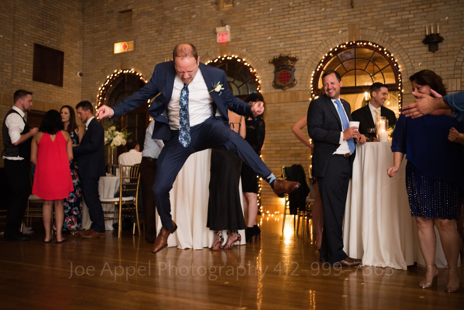A man in a blue suit leaps into the air while dancing during a St Francis Hall Washington DC wedding.