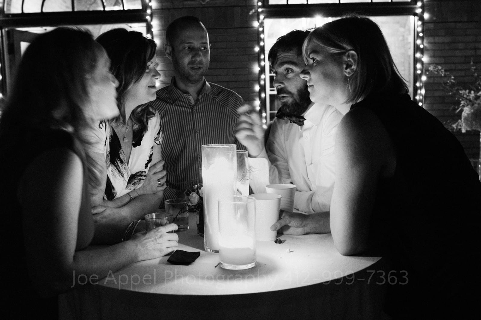 Wedding guests gather around a candle on a high top table as they chat during a St Francis Hall Washington DC wedding.