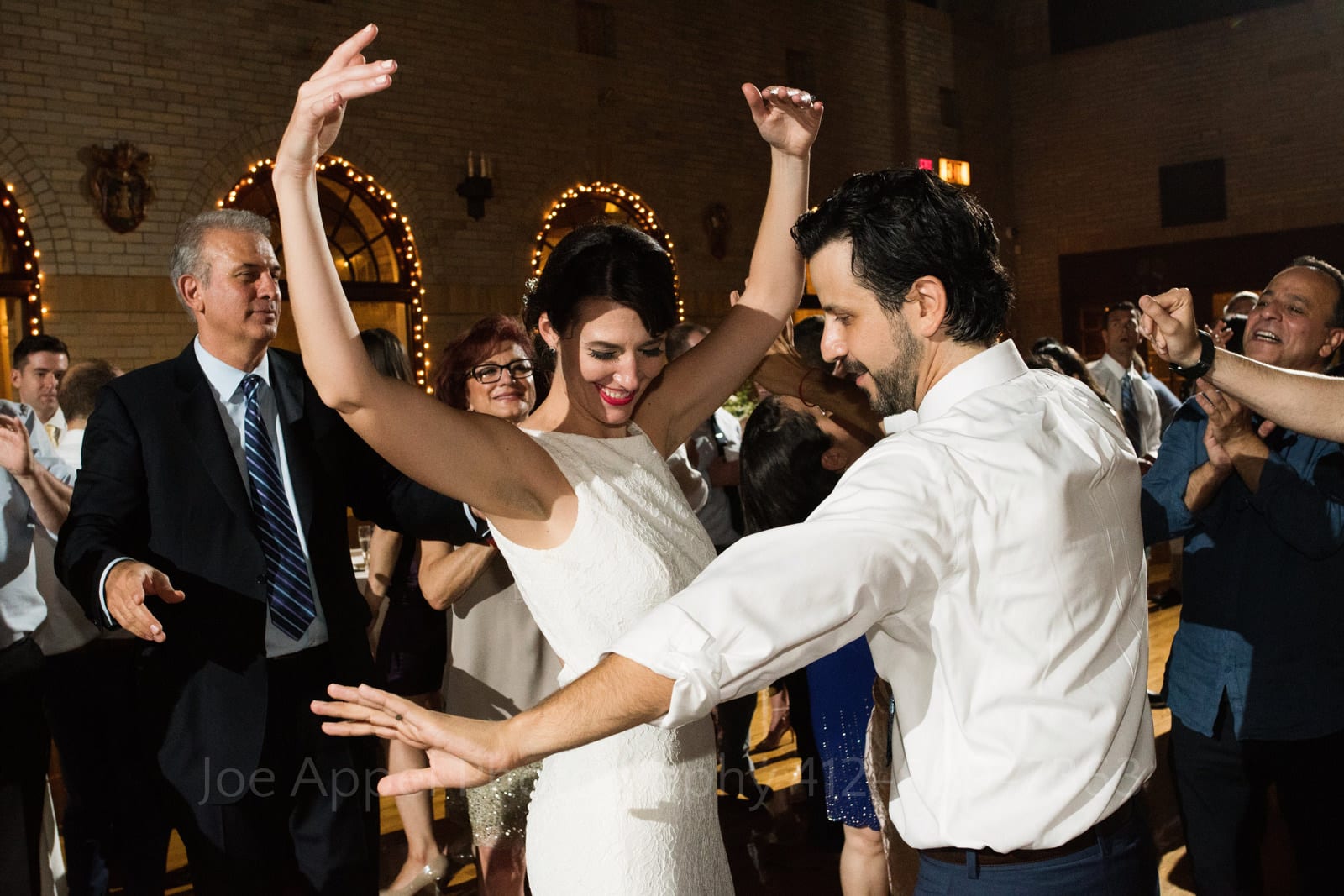 A bride holds her hands in the air while dancing with her groom whose arms are outstretched during their St Francis Hall Washington DC wedding.