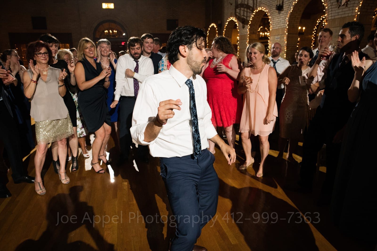 A sweaty groom dances in front of a group of wedding guests during a St Francis Hall Washington DC wedding.