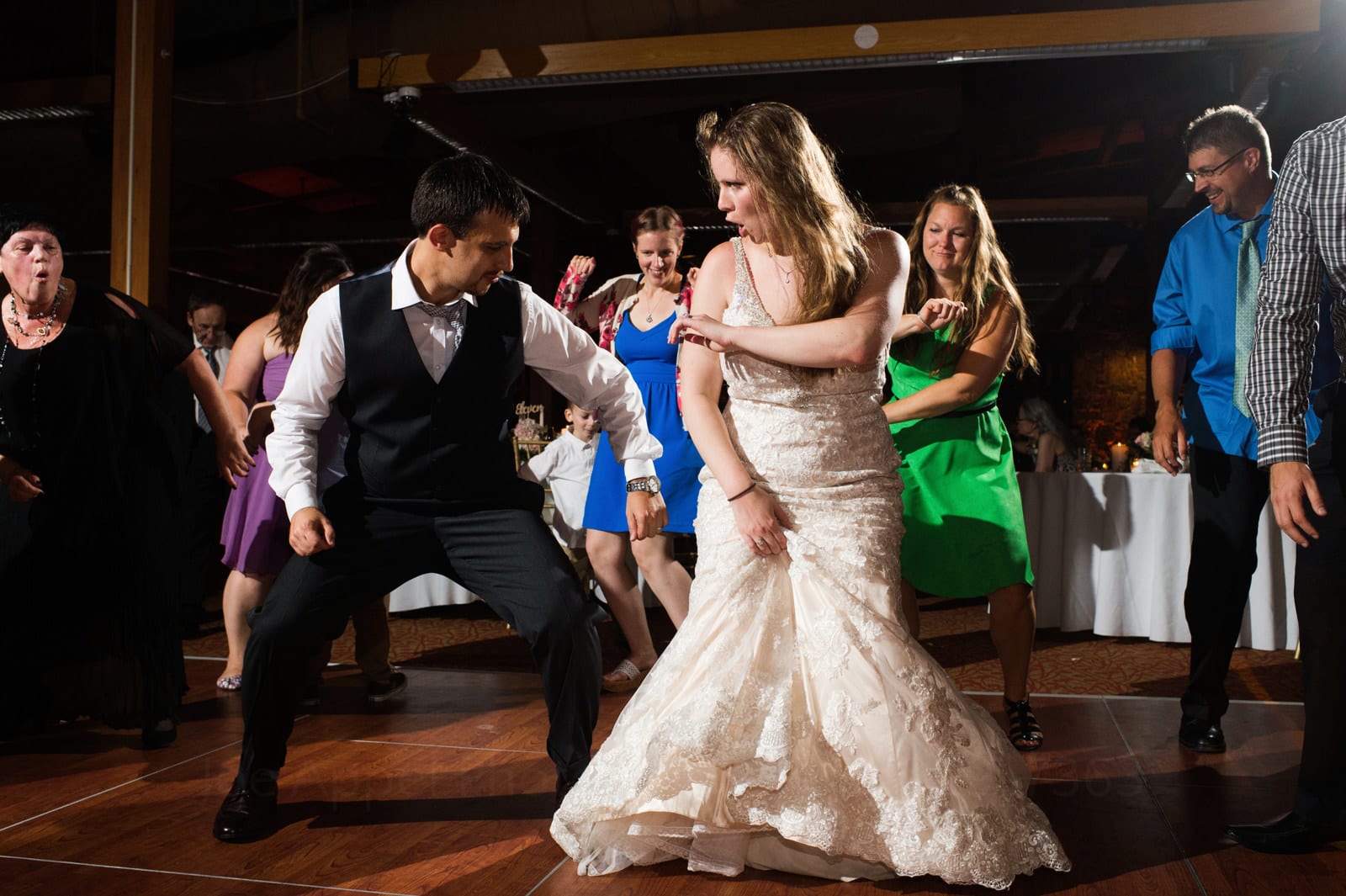 A bride and groom dance side by side while surrounded by guests during their fall wedding at Seven Springs.