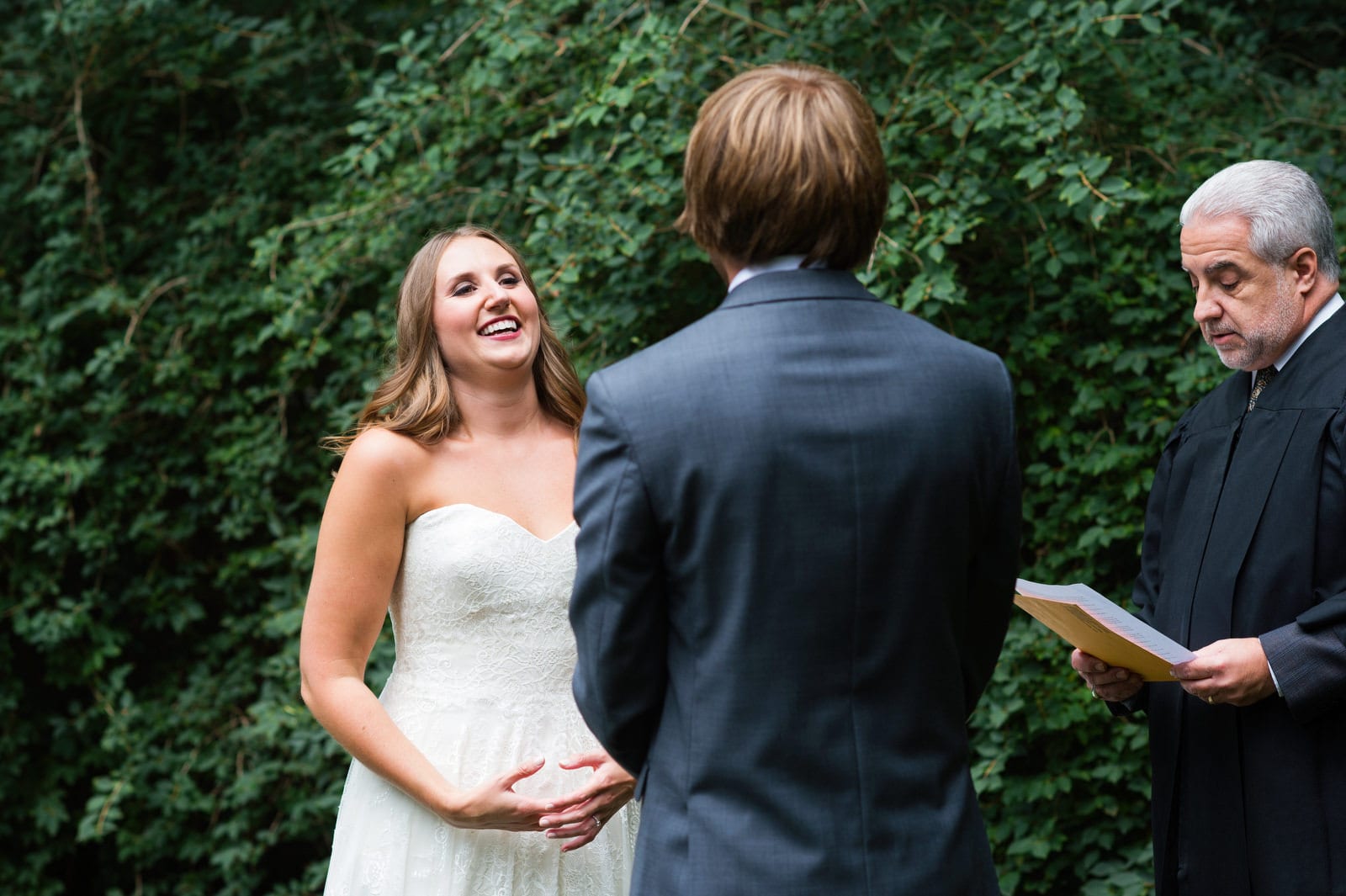 A bride smiles while saying her vows in a clearing in the woods during her Hyeholde Wedding Pittsburgh.