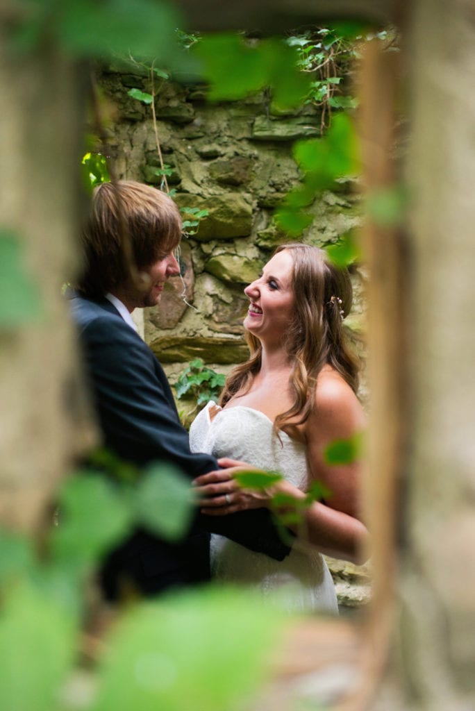 A bride and groom embrace inside of a small stone building during their Hyeholde Wedding Pittsburgh.