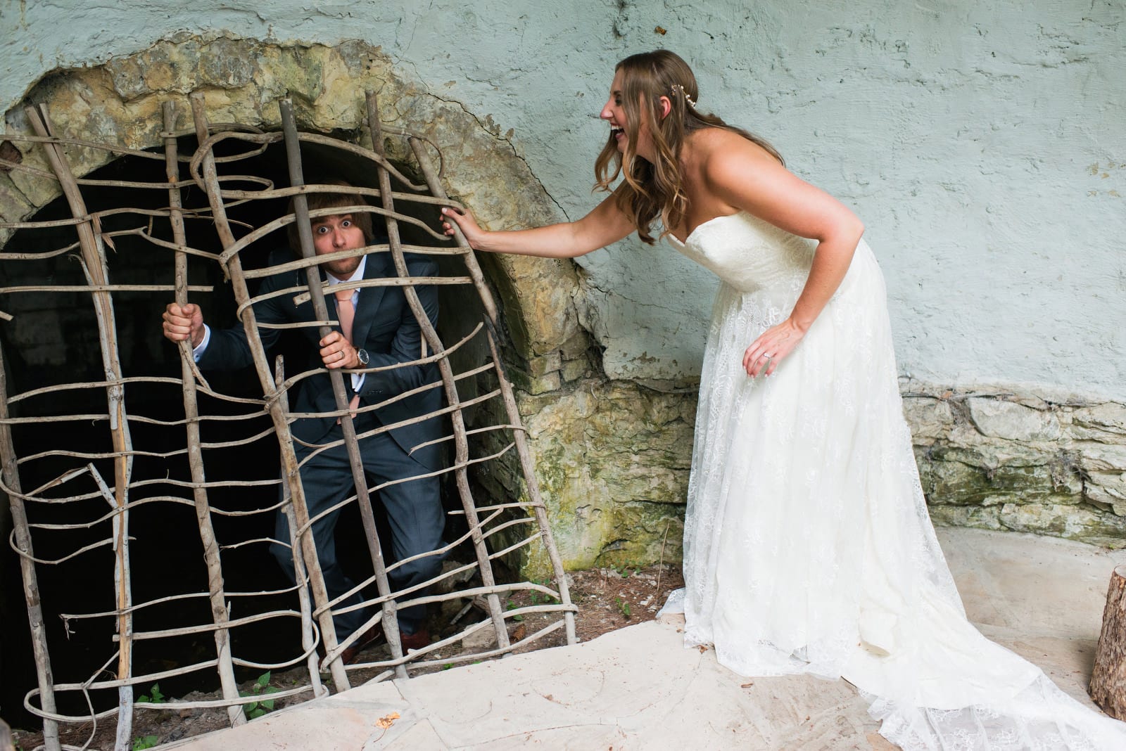 A bride and groom goof around as the groom pretends that he's trapped inside of a wooden grate during their Hyeholde Wedding Pittsburgh.