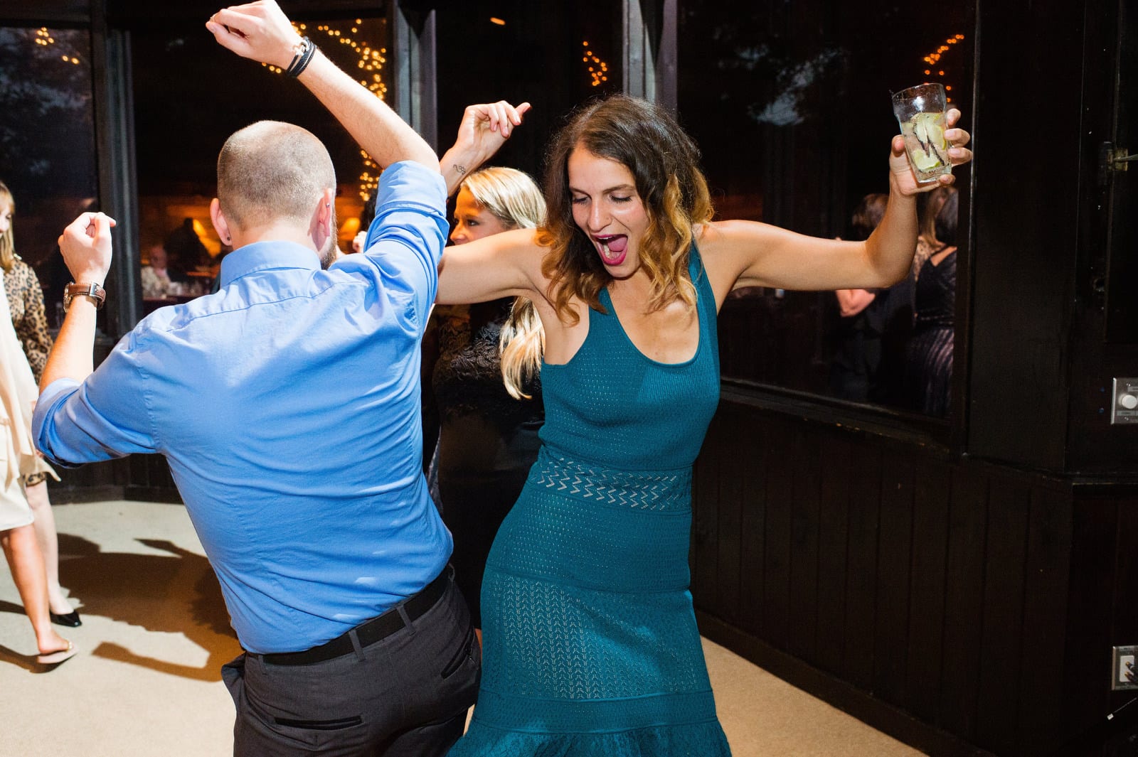 A woman in a blue dress bumps hips with a man in a blue shirt as they dance during a Hyeholde Wedding Pittsburgh.