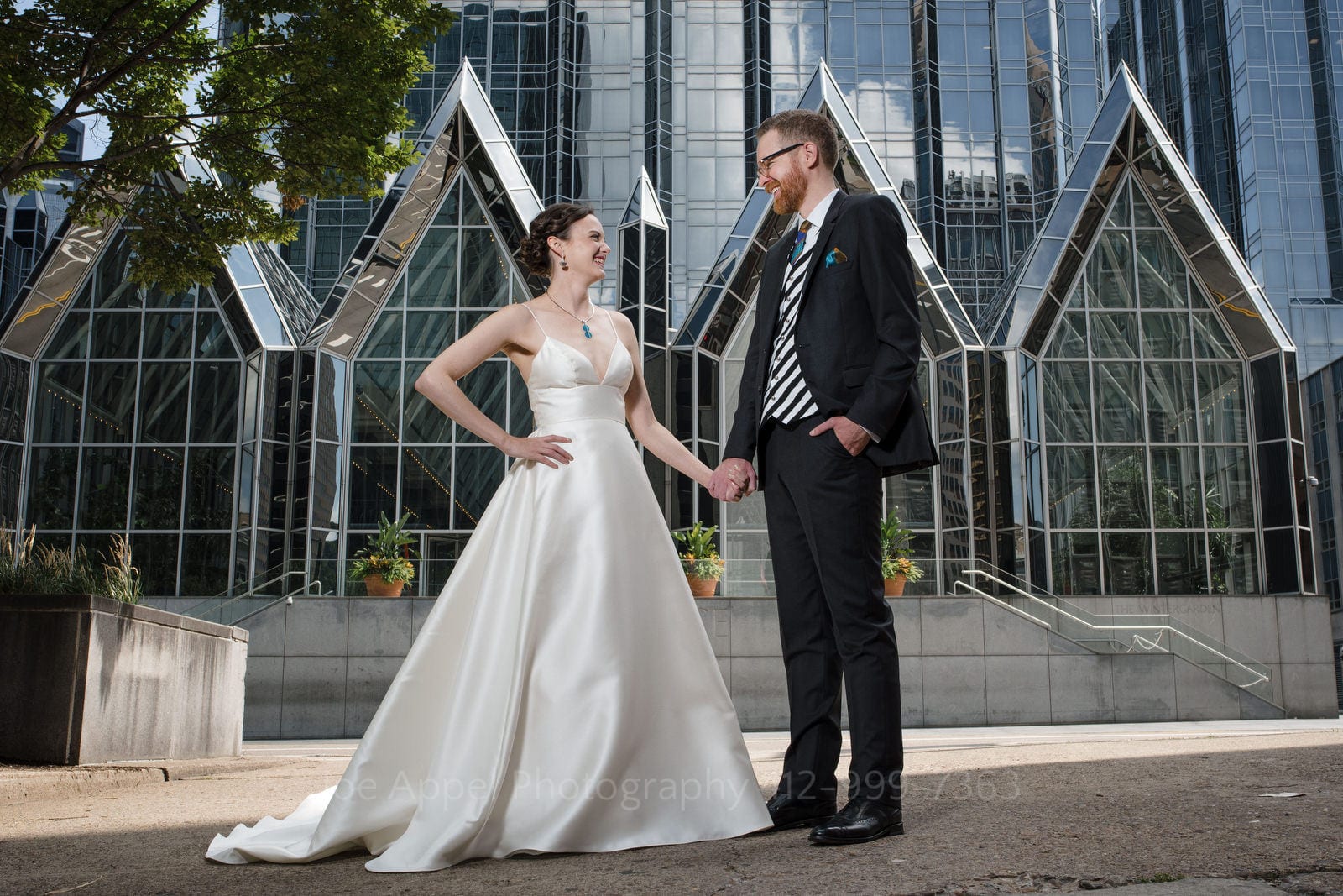 A bride and groom hold hands as they stand in front of PPG Place in downtown Pittsburgh.