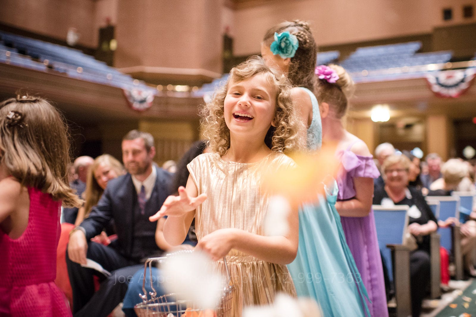 A smiling flower girl throws petals at the camera during Soldiers and Sailors Wedding Photos.