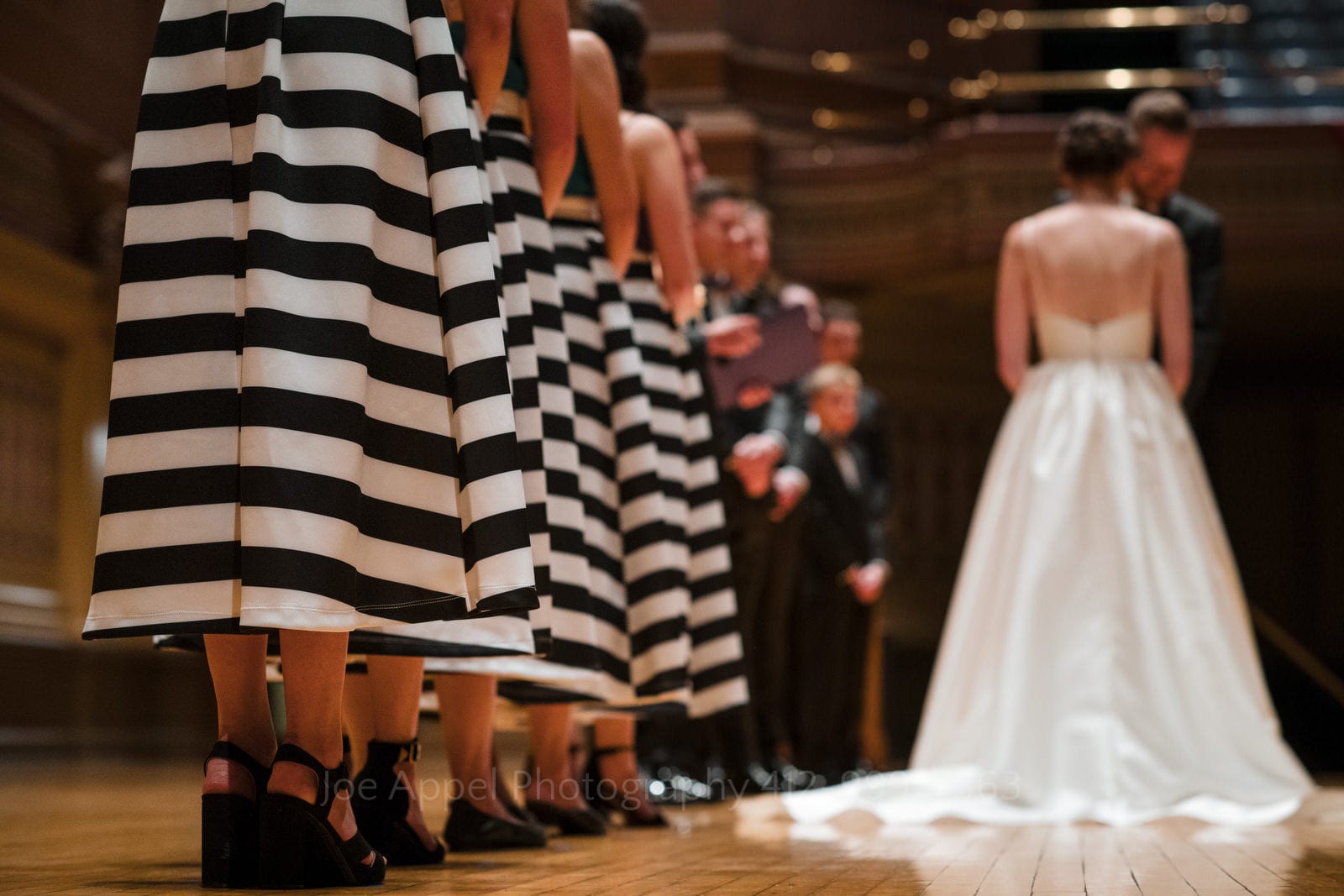 Bridesmaids wearing black and white striped skirts stand on the stage during Soldiers and Sailors Wedding Photos.