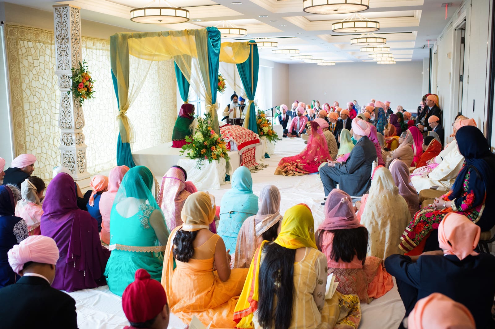 A group of colorfully dressed people attend a Renaissance Phipps South Asian Wedding.