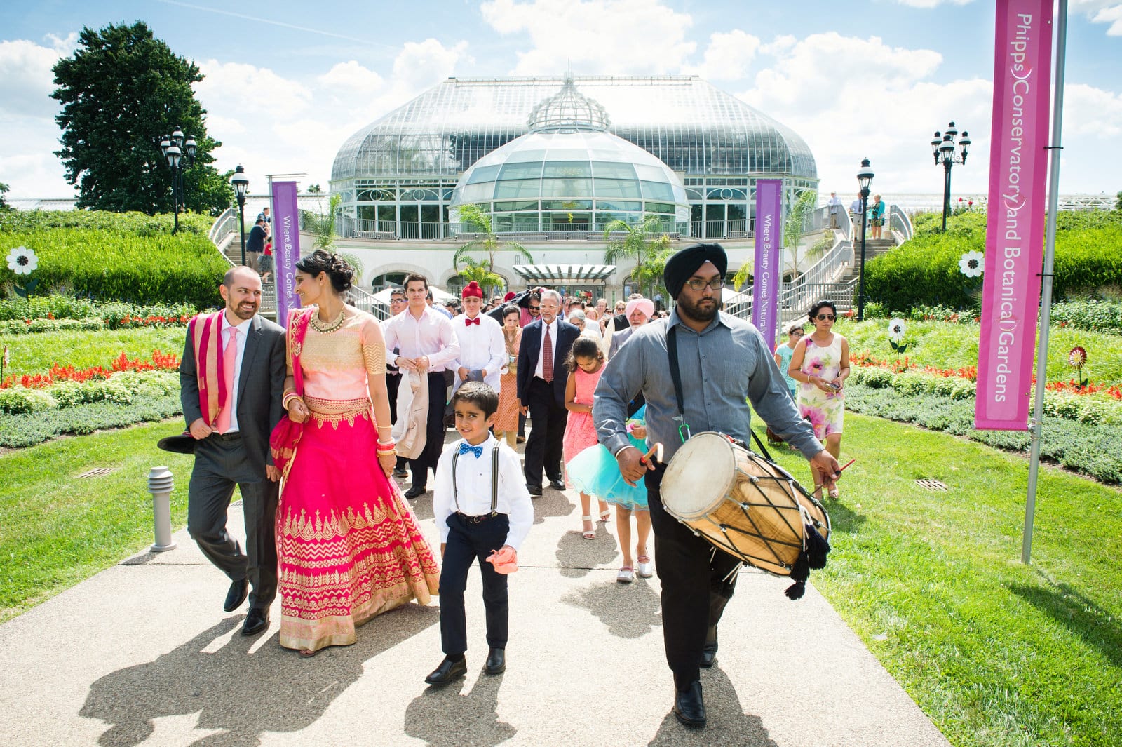 A drummer leads a bride and groom from the entrance at Phipps Conservatory after their Renaissance Phipps South Asian Wedding.
